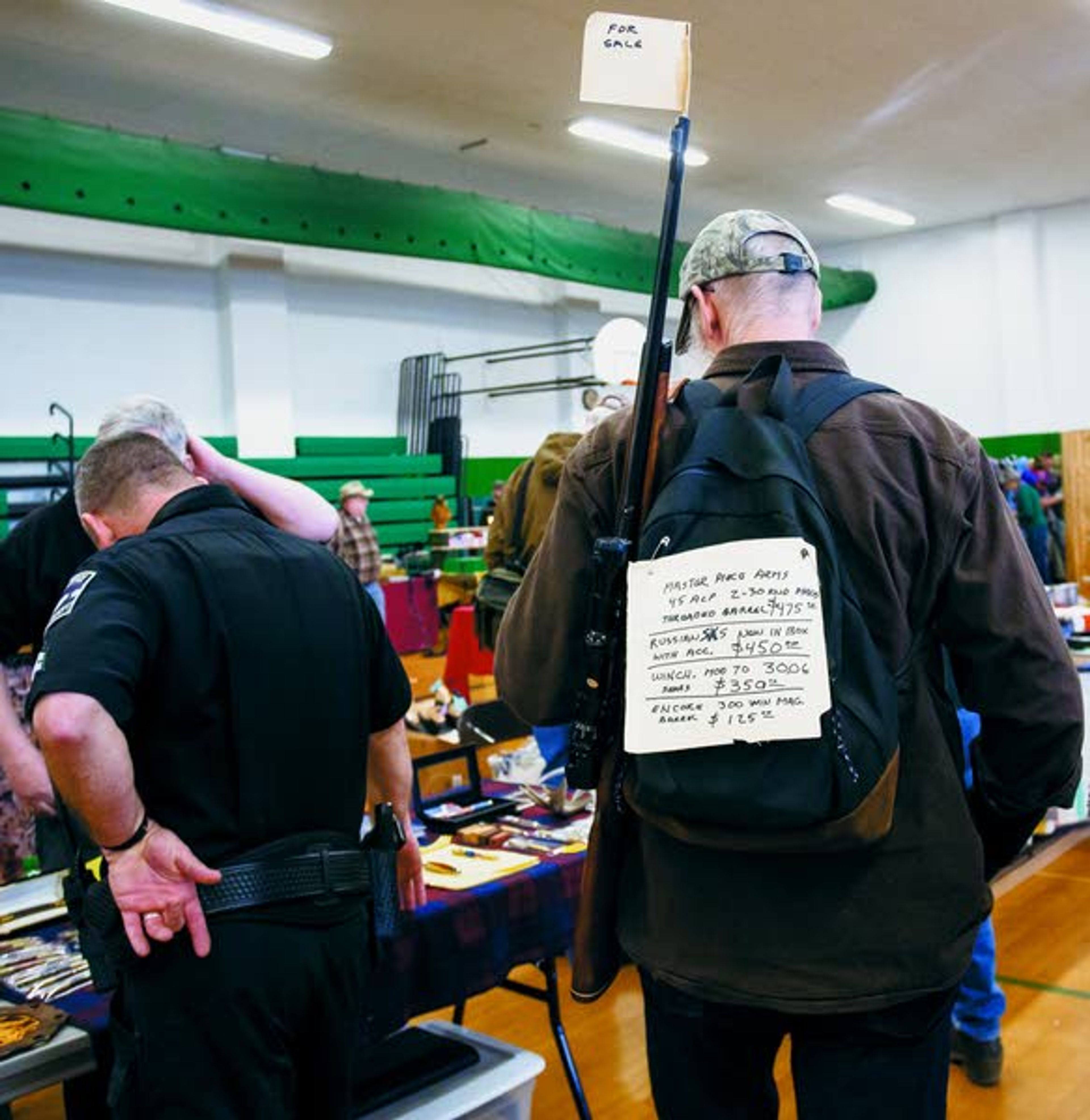 A man advertises the firearms and components he has for sale as he walks through the Potlatch gun show on Sunday, March 16, 2014, at Potlatch Elementary School.