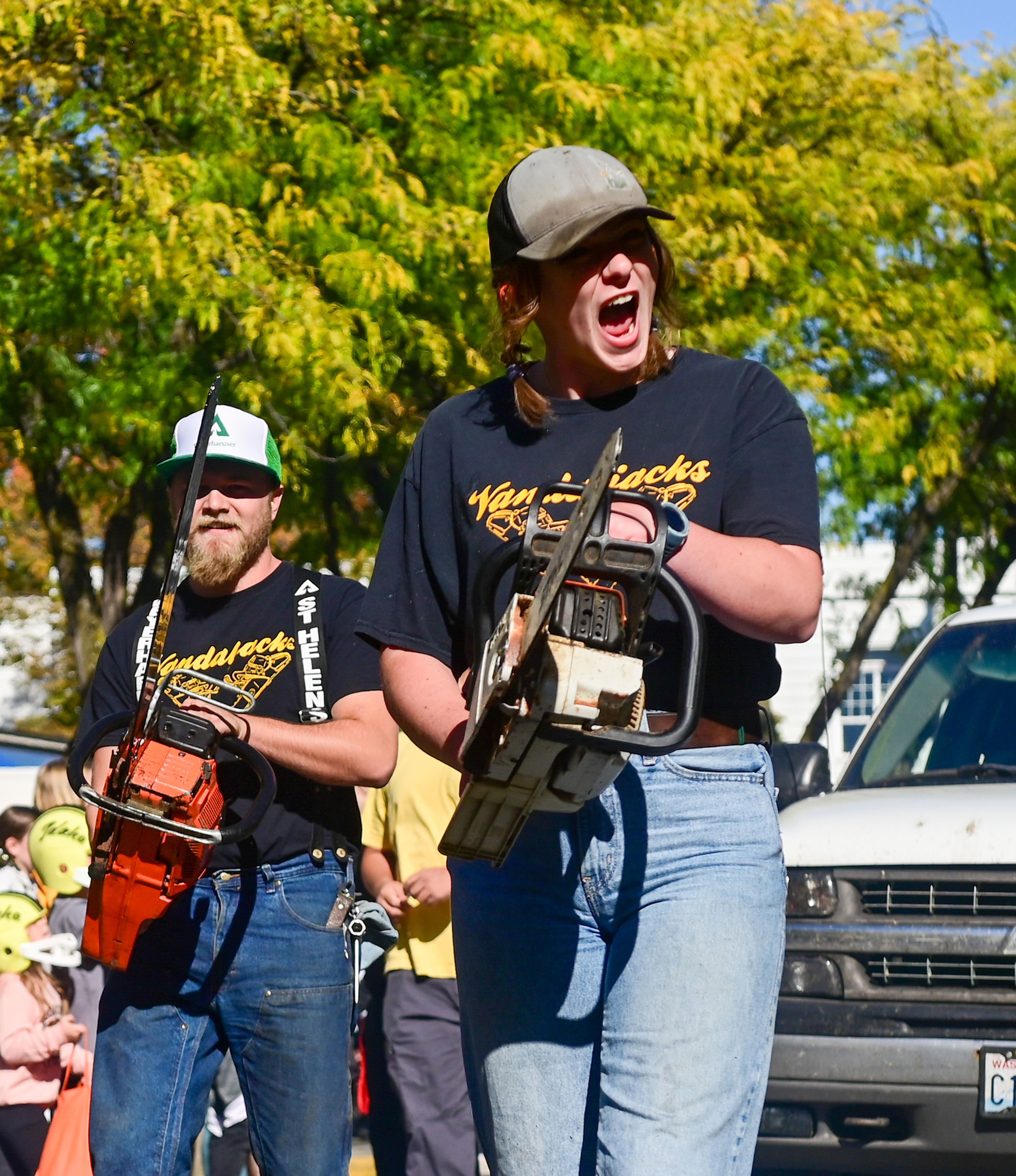 Members of the Vandaljacks, the University of Idaho Timbersports Team, raise chain saws as they walk along Main Street as part of the homecoming parade Saturday in Moscow.