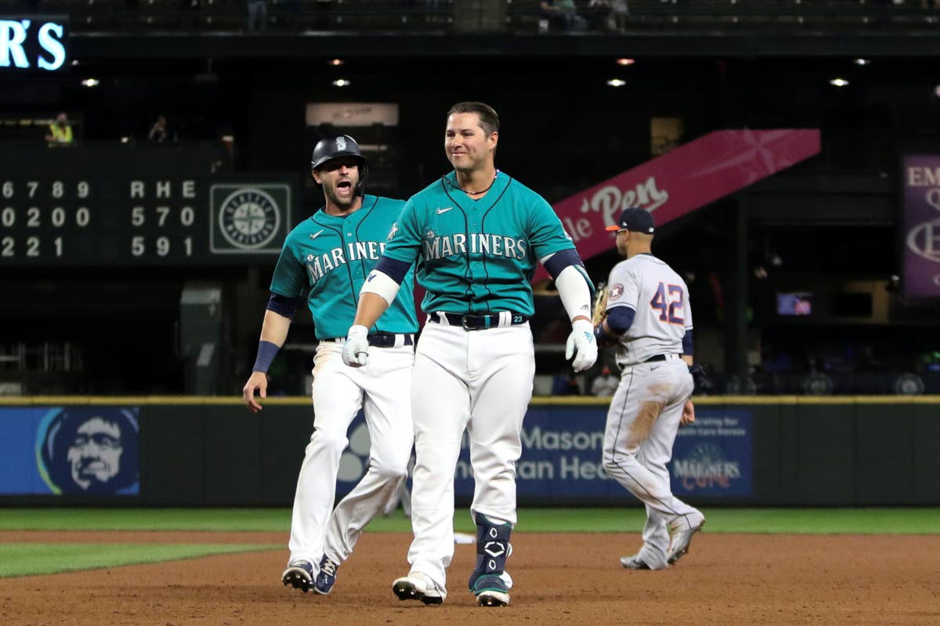 Seattle Mariners' Ty France, right, and Mitch Haniger react after France drove in the winning run with a single during the ninth inning of the team's baseball game against the Houston Astros on Friday, April 16, 2021, in Seattle. The Mariners won 6-5. (AP Photo/Jason Redmond)