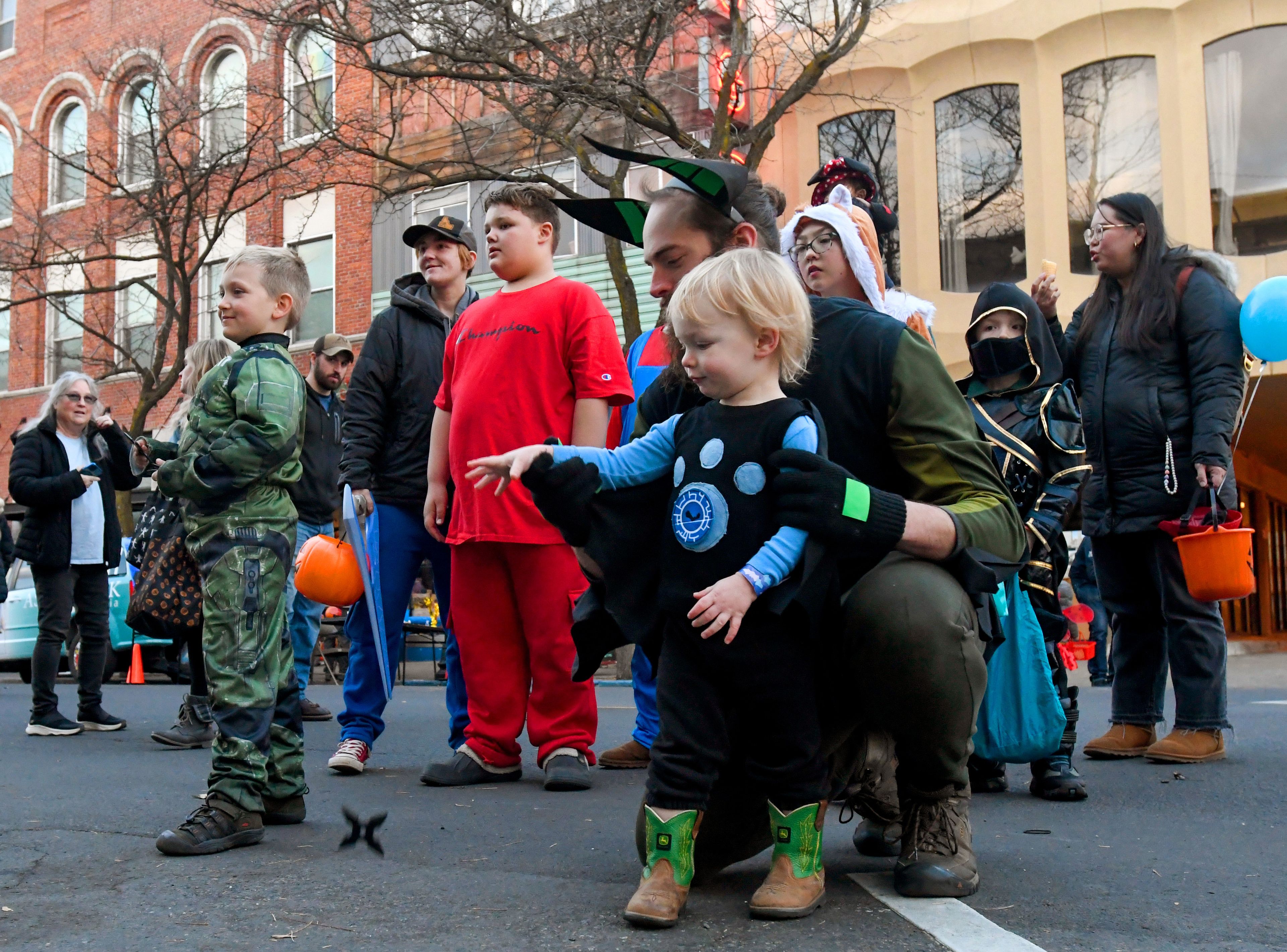 Felix Hammerich, right, 2, is helped by Charlie Hammerich to throw a plastic blade at a foam target brought by Moscow Axe Throwing to Moscow’s Downtown Trick-or-Treat on Tuesday.