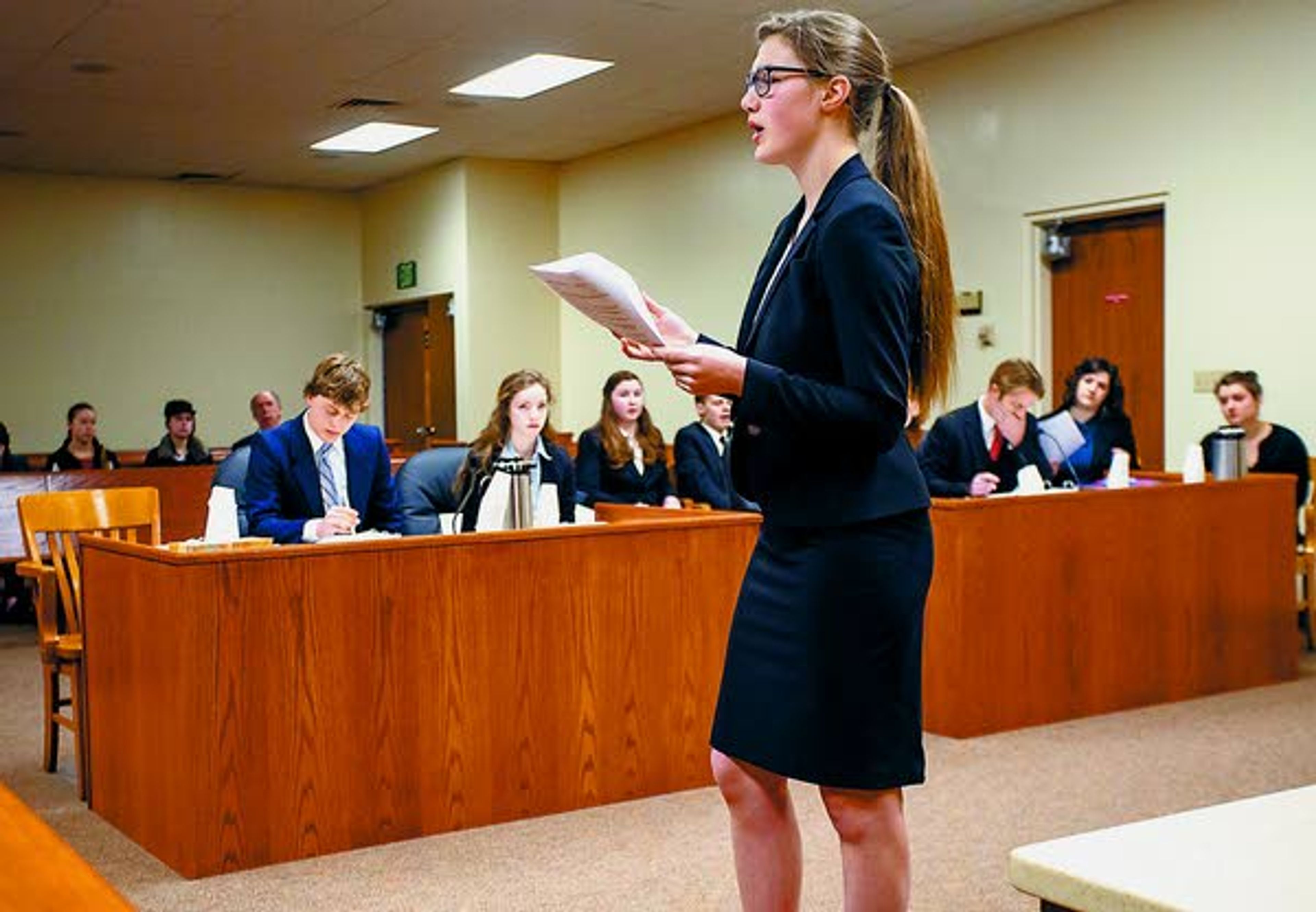 Sonya Isenberg, standing, presents opening arguments to the jury for the Logos School Mock Trial Team, at left table, Saturday during a scrimmage against a group of Logos mock trial alumni, at right table, at the Latah County Courthouse. Latah County prosecutor Bill Thompson acted as judge during the scrimmage.