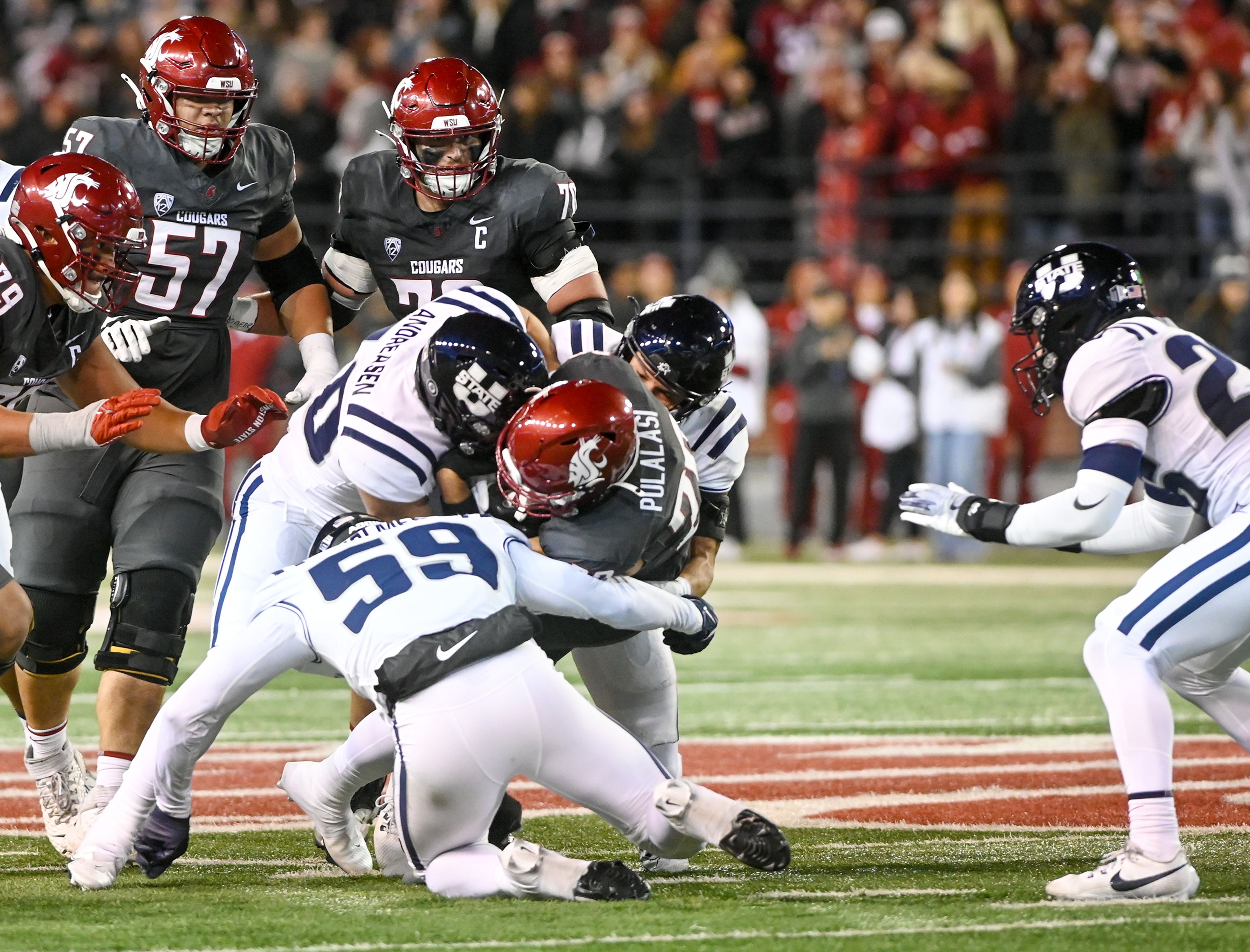 Washington State running back Leo Pulalasi (20) is tackled by Utah State defenders Saturday at Gesa Field in Pullman.