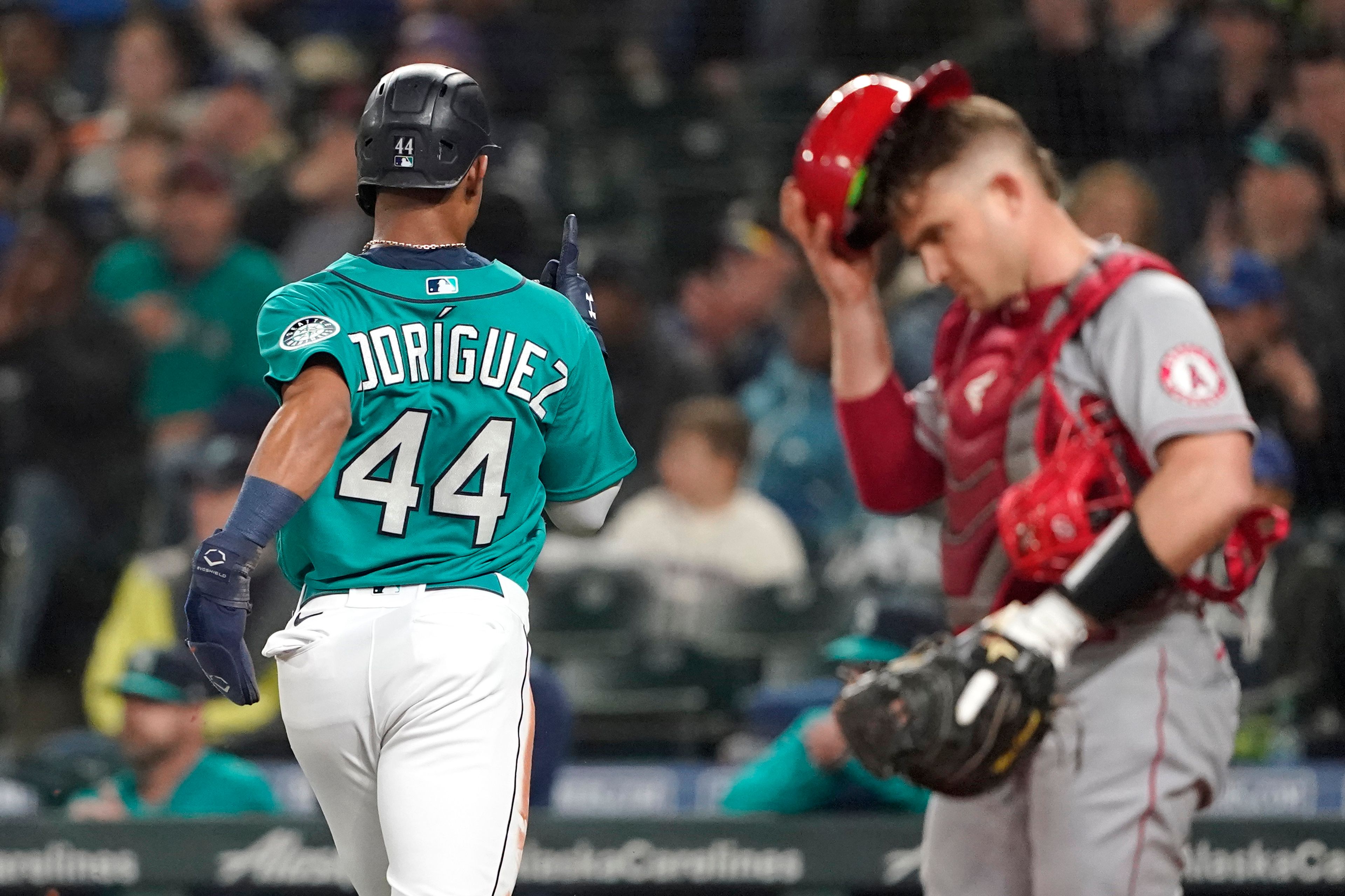 Seattle Mariners' Julio Rodriguez reacts as he crosses the plate in front of Los Angeles Angels catcher Max Stassi, right, scoring a run on an RBI-single hit by Eugenio Suarez during the first inning of a baseball game, Friday, June 17, 2022, in Seattle. (AP Photo/Ted S. Warren)