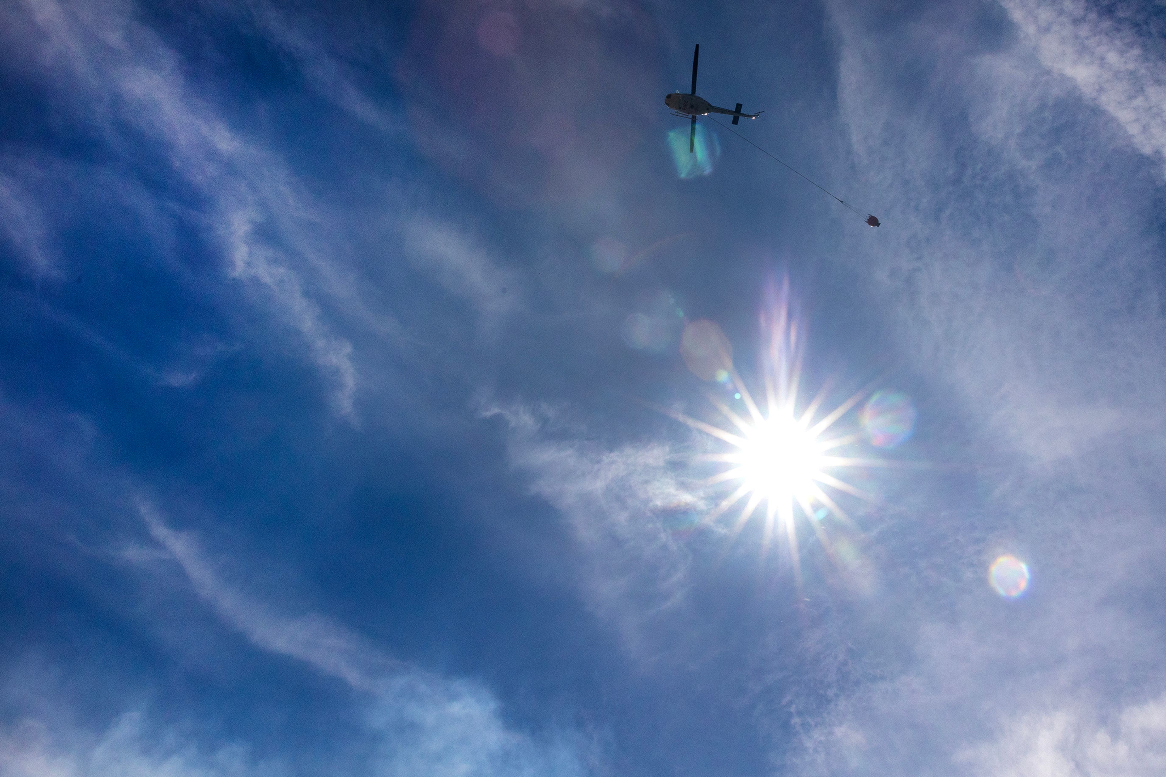 A helicopter flies towards the fire to make a drop nearby Nisqually John Landing off of Wawawai Road on Friday.