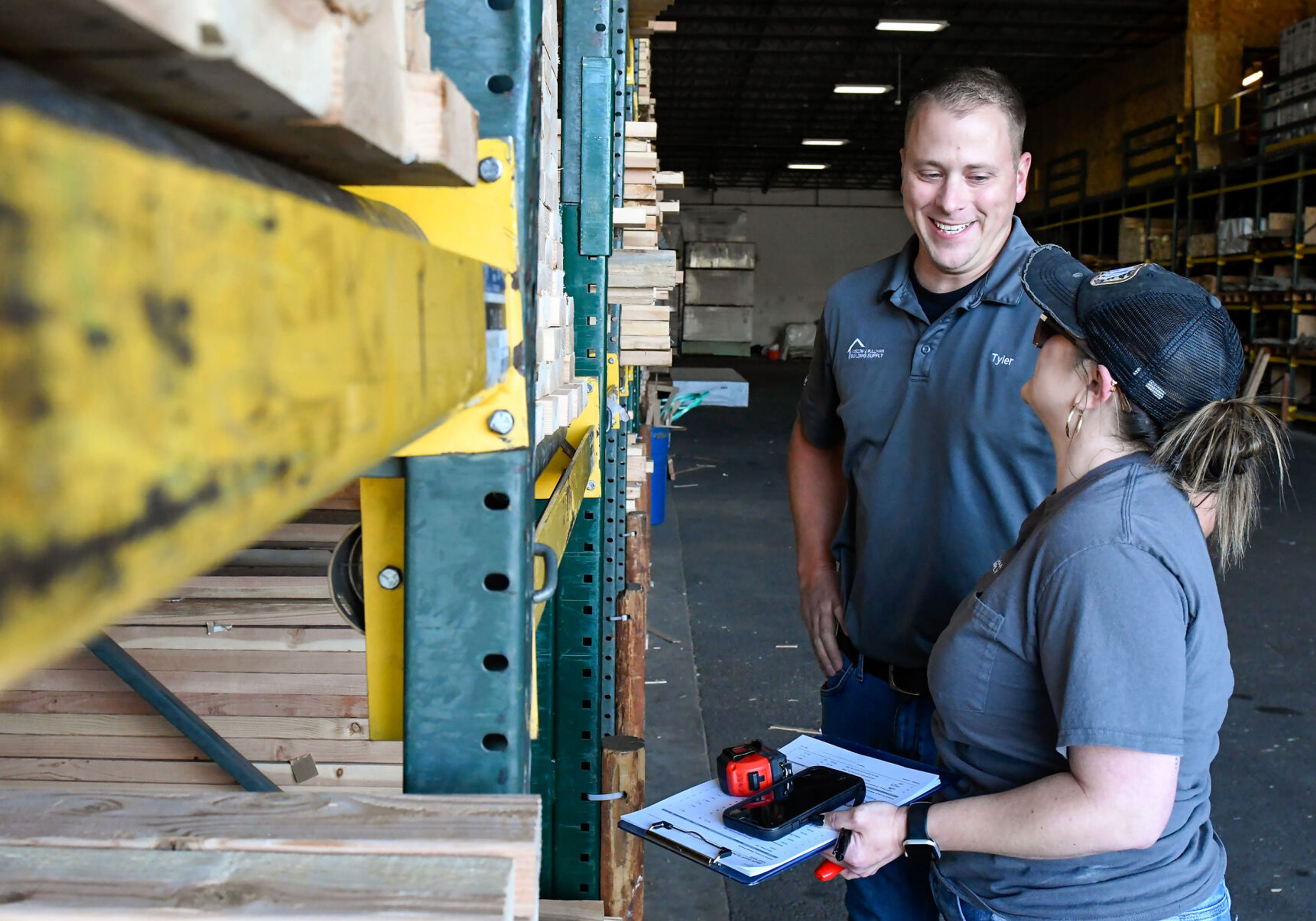 Tyler Garrett, president and CEO of Moscow & Pullman Building Supply, speaks with Cassey Polillo, right, an inventory control specialist, at Moscow Building Supply on Wednesday.