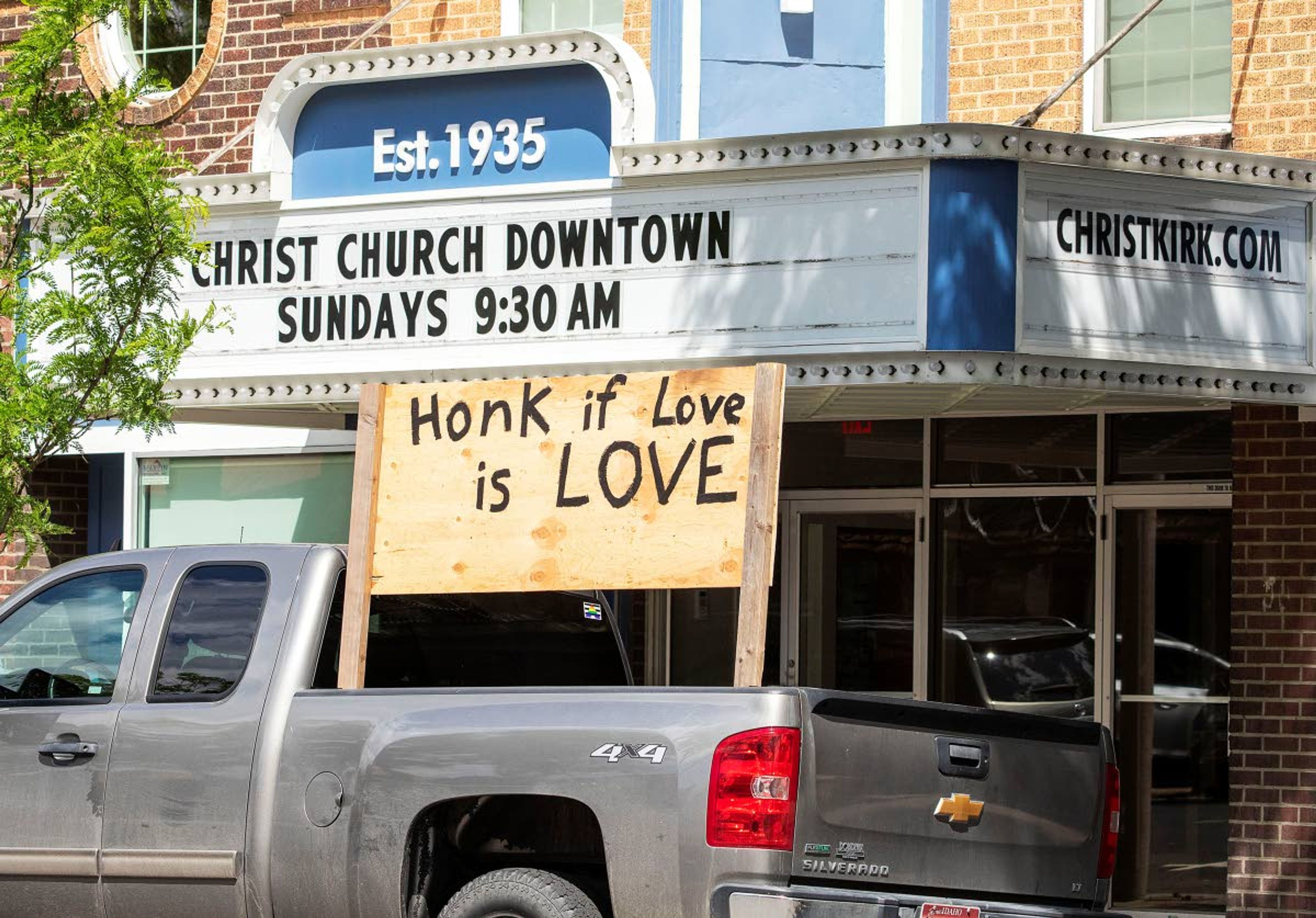 A sign reading “Honk if love is love” stands in the back of a pickup parked outside Christ Church on Tuesday on Main Street in Moscow.