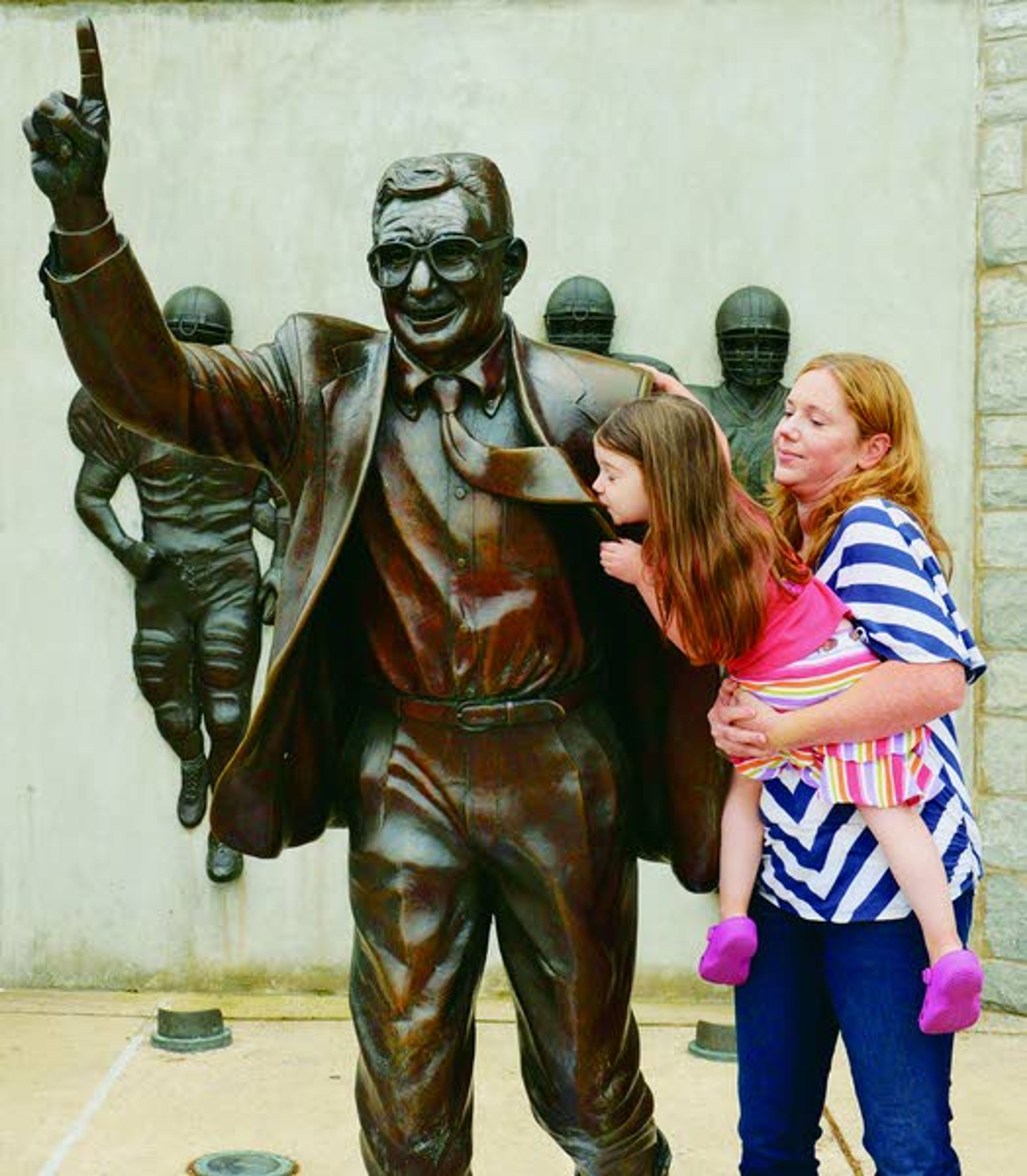 Jenni Kahler, right, holds her daughter, Emma, 4, as they have a photo taken with the statue of Joe Paterno located outside Beaver Stadium. in State College, Pa., Friday July 20, 2012. Paterno's statue stands outside the stadium even as his reputation has swiftly fallen following a scathing special investigative report that found he helped cover up child sex abuse allegations against former defensive coordinator Jerry Sandusky. (AP Photo/John Beale)