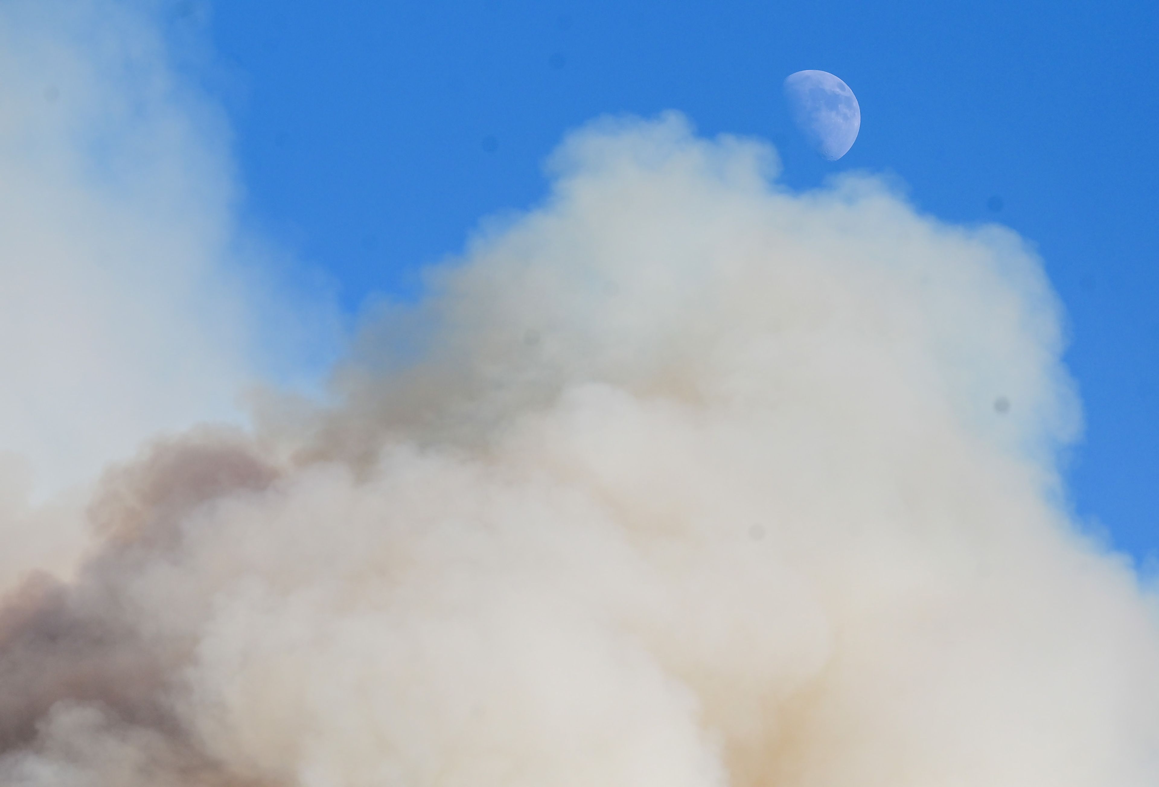 Smoke begins to cover a view of the moon as the smoke rises from a canyon in the area of Texas Ridge and Cedar Ridge roads where a wildfire burns near Kendrick on Monday.