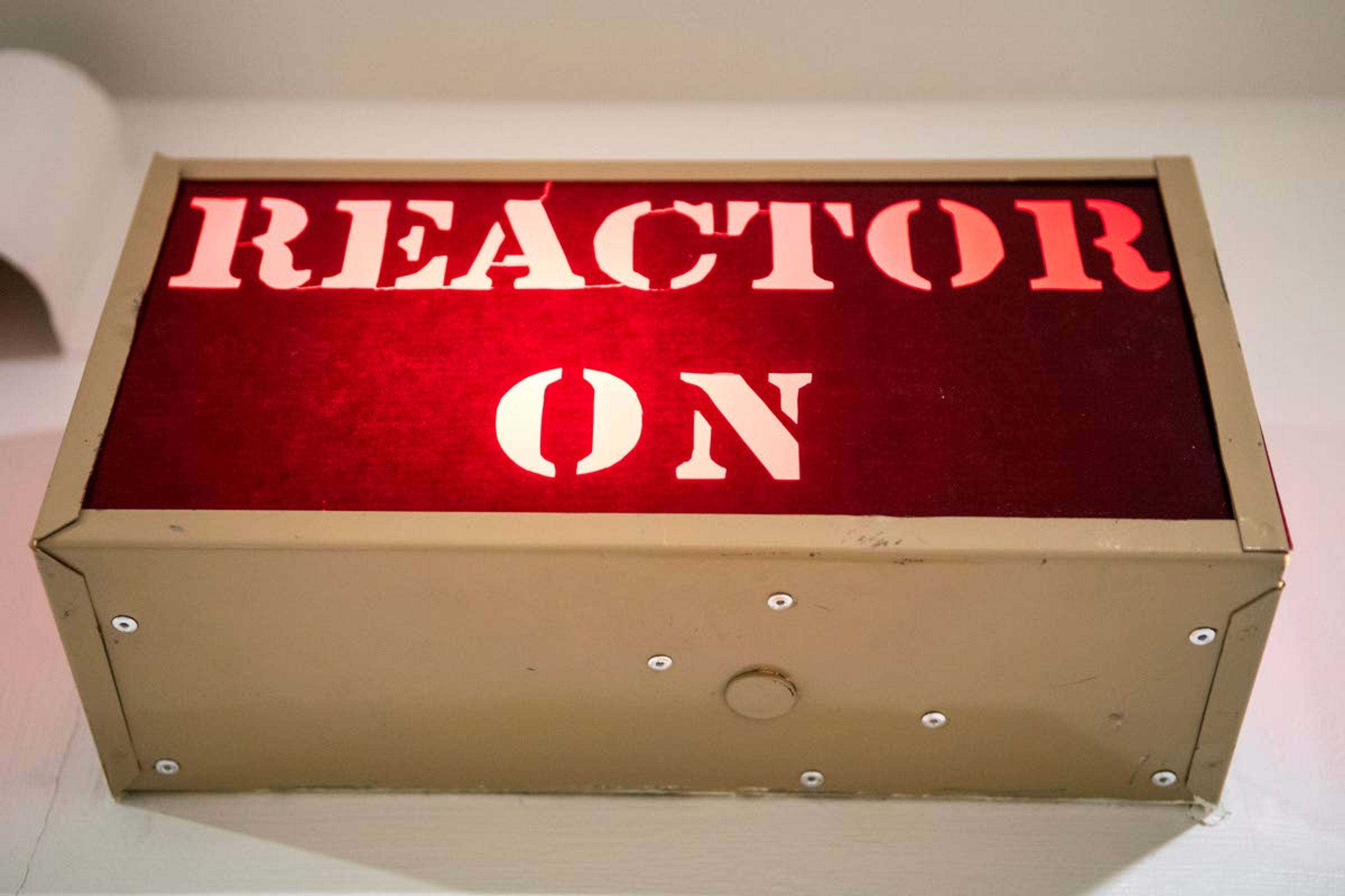 A sign reading “Reactor On” is lit with a red glow outside of the reactor control room at Washington State University’s Nuclear Science Center.