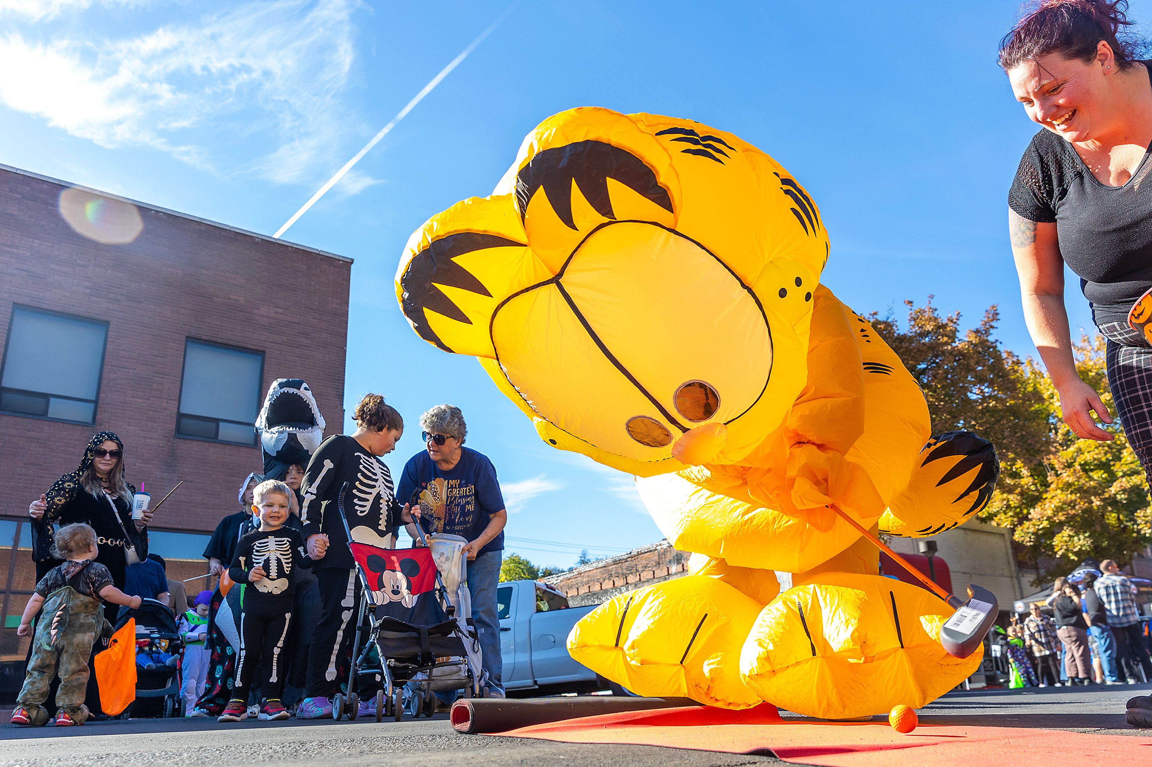 Mayaja Dinnell, of Lewiston, attempts to golf dressed as Garfield Saturday at Pumpkin Palooza in downtown Lewiston.,