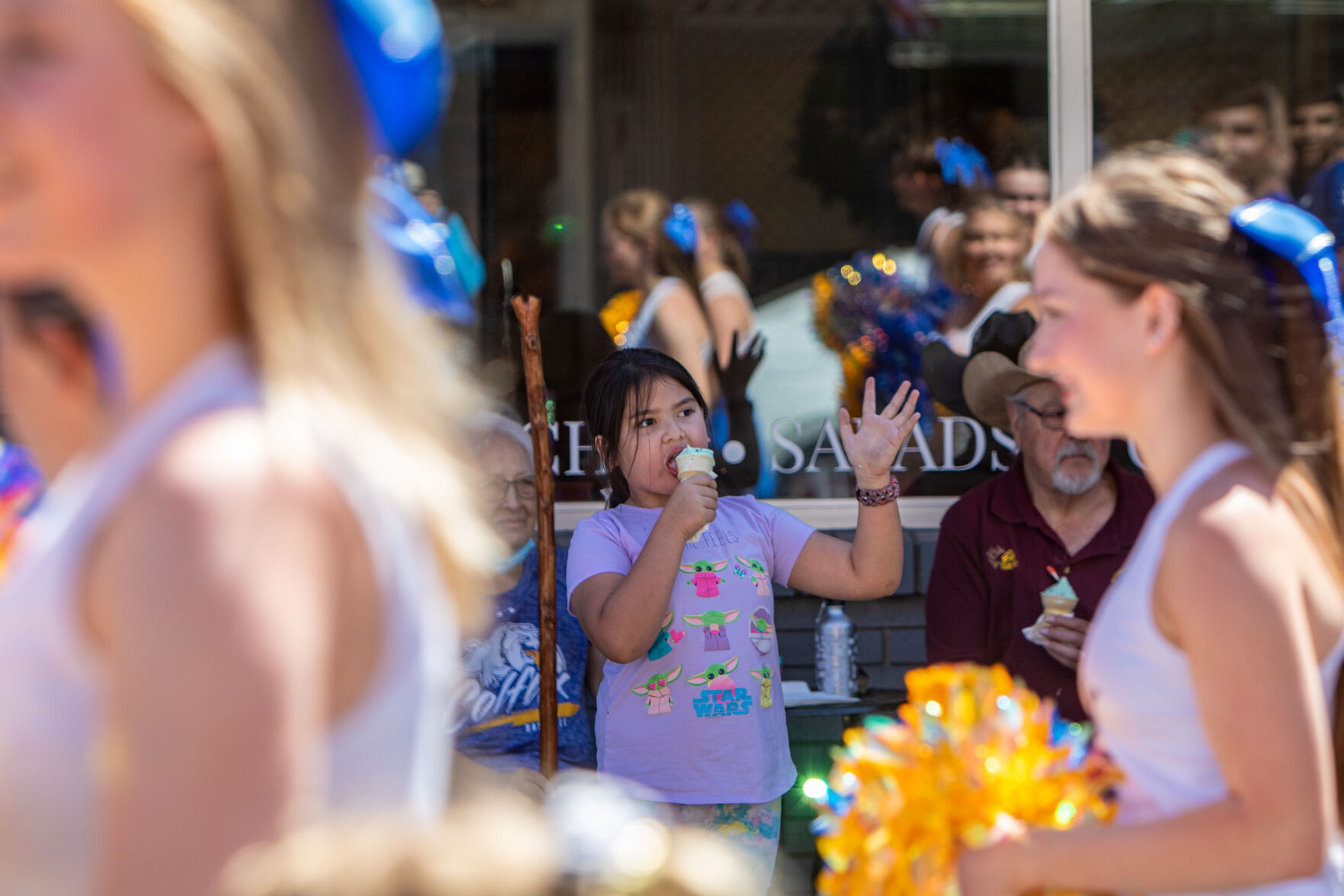 A girl enjoys some ice cream while waving to the children’s parade Saturday during the city of Colfax’s 150th birthday celebration.