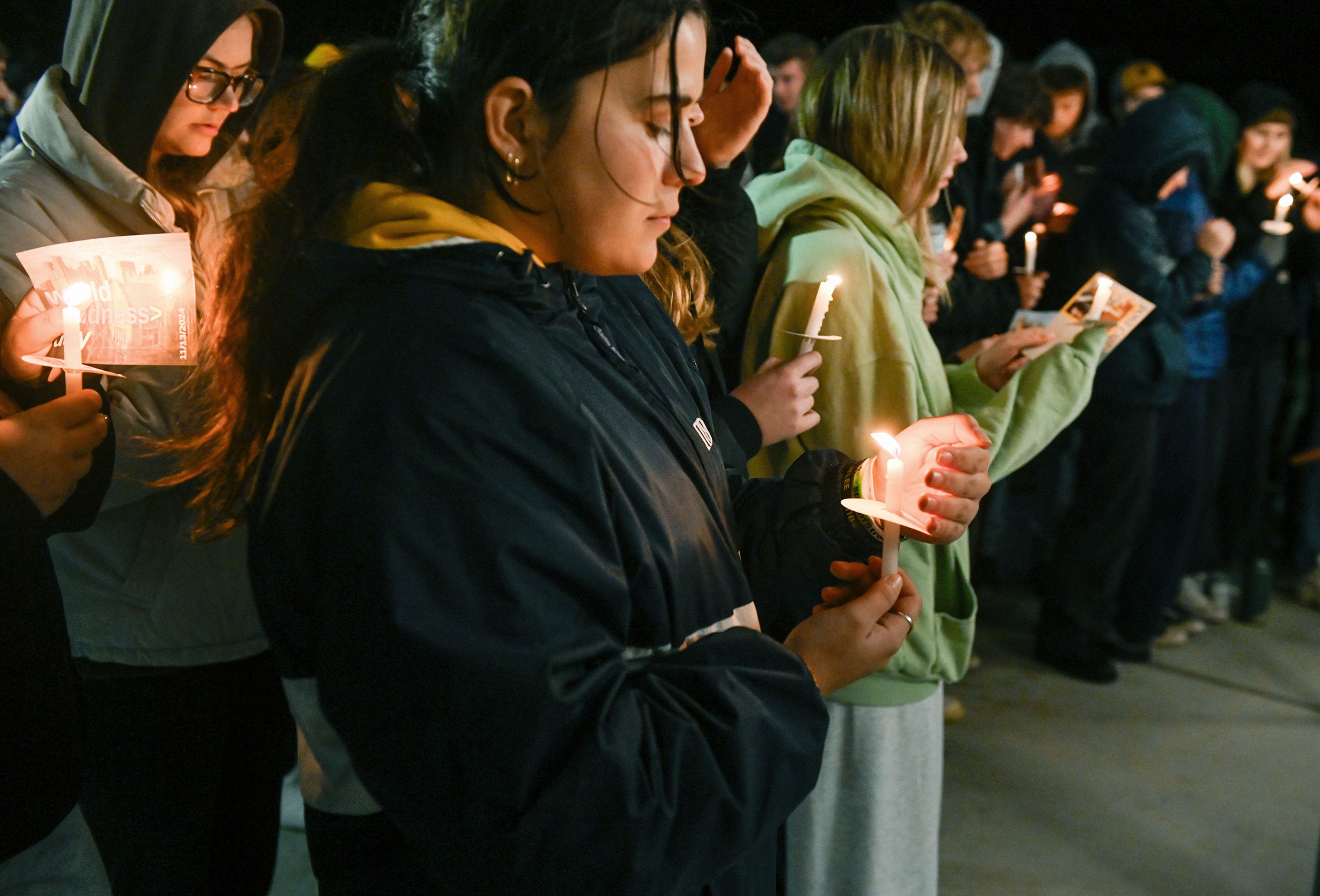 Rebekah Boyd, center, looks down at the flame of her candle during a vigil held Wednesday at the Vandal Healing Garden and Memorial to remember the four University of Idaho students murdered two years ago in Moscow.