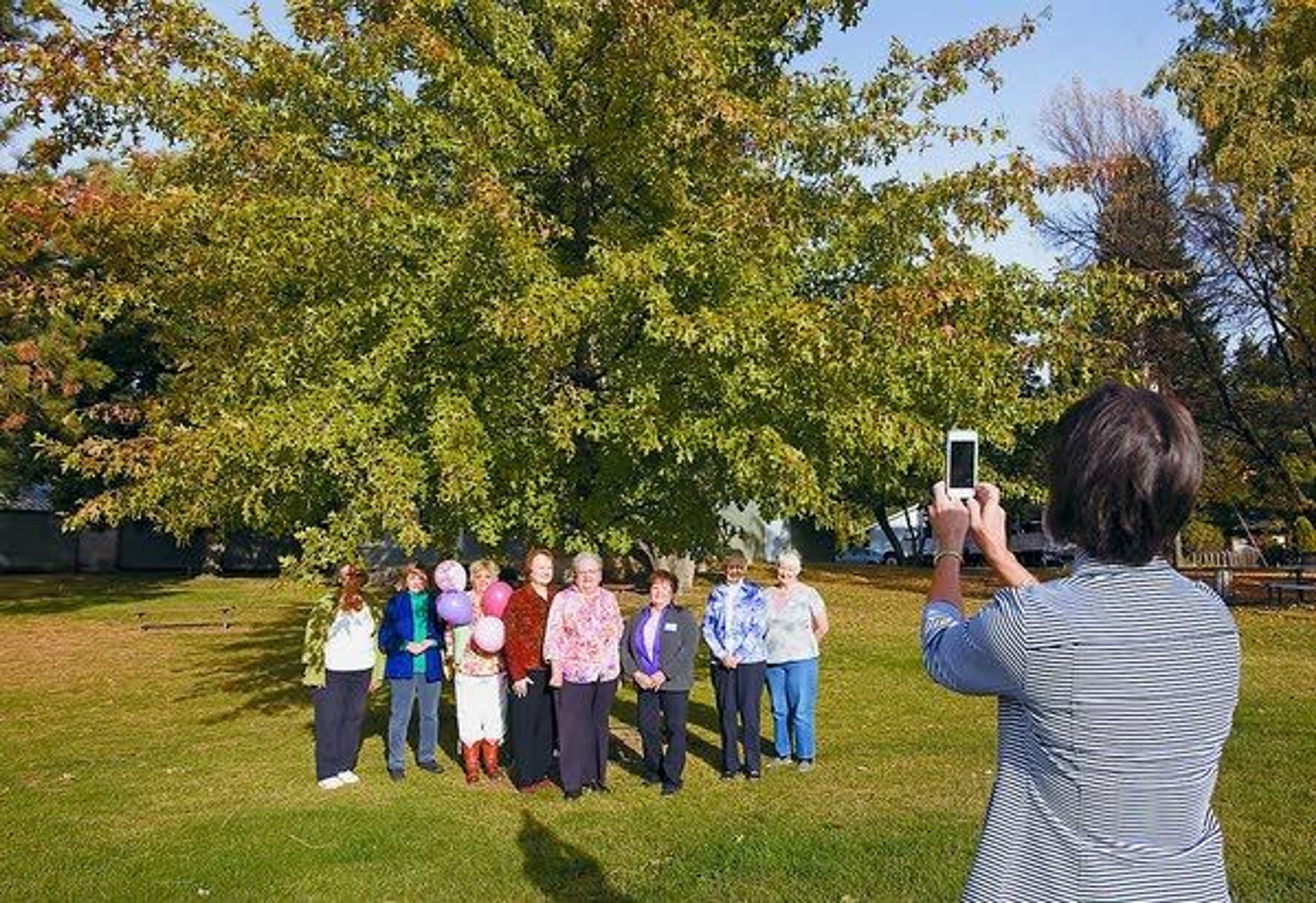 Janet Petersen, right, photographs members of the Moscow Garden Club under the Appomatox Pin Oak they planted fifteen years ago at the Latah County Fairgrounds in Moscow on Thursday. The club is celebrating it's 65th anniversary this month. Petersen is president of Garden Clubs of Idaho.