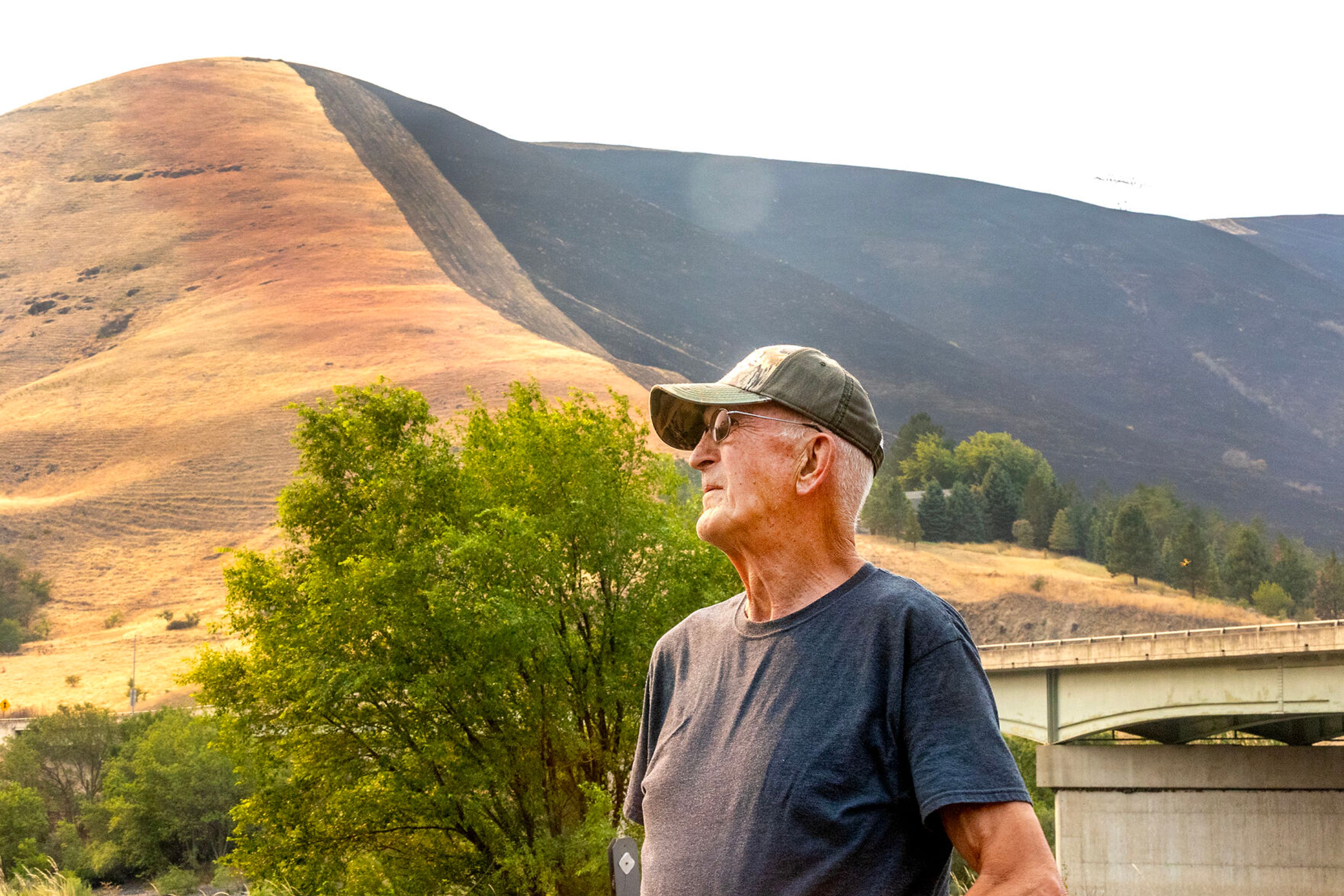 Arrow Junction Fire Protection District Fire Chief Gene Wightman looks on outside the fire station as the northern hillside displays the burn marks from the Gwen Fire on Friday.