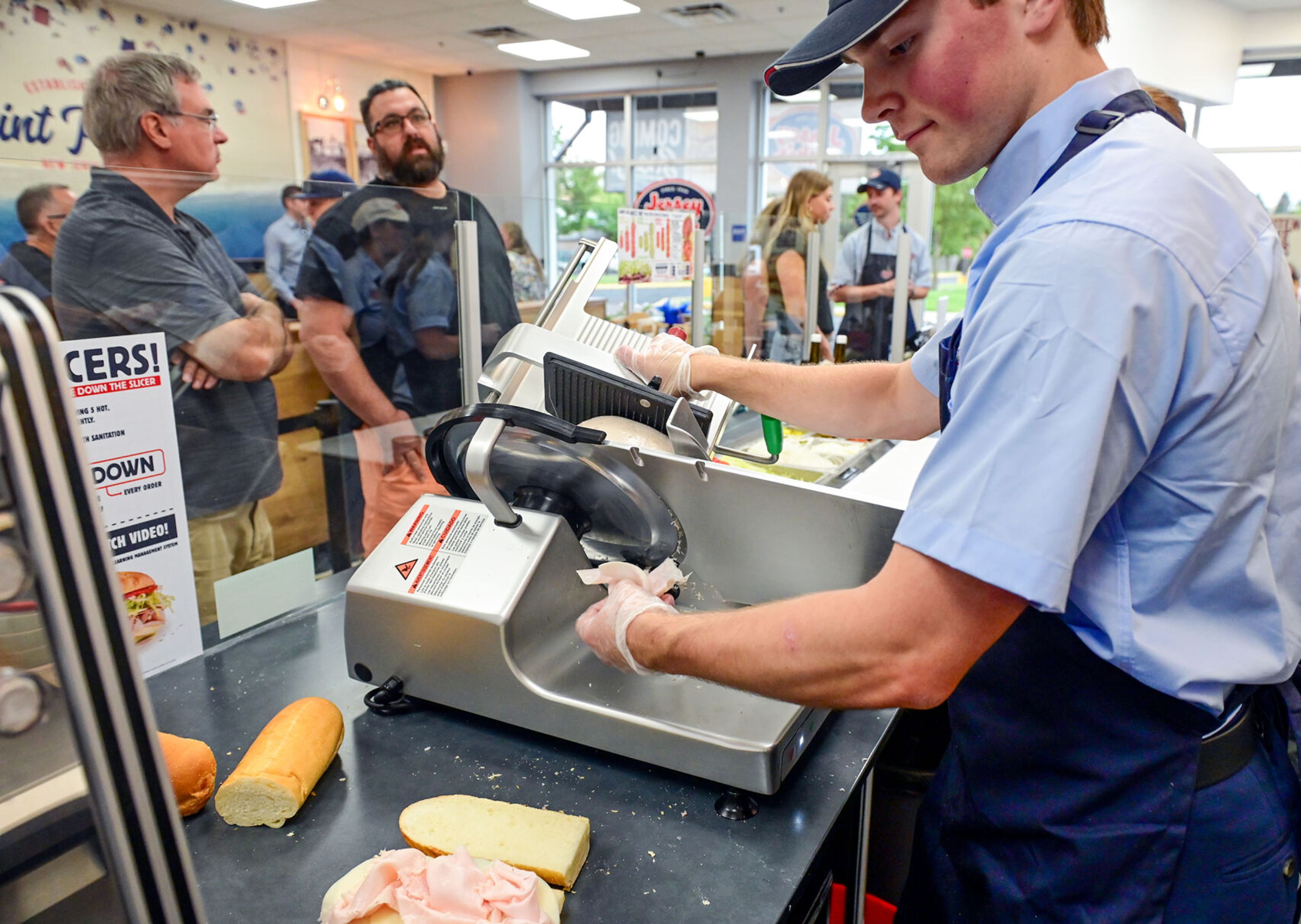 Crew member Preston Blumhagen slices meat for sandwich orders during a friends and family soft opening at the new Jersey Mike's Subs on Tuesday in Moscow.