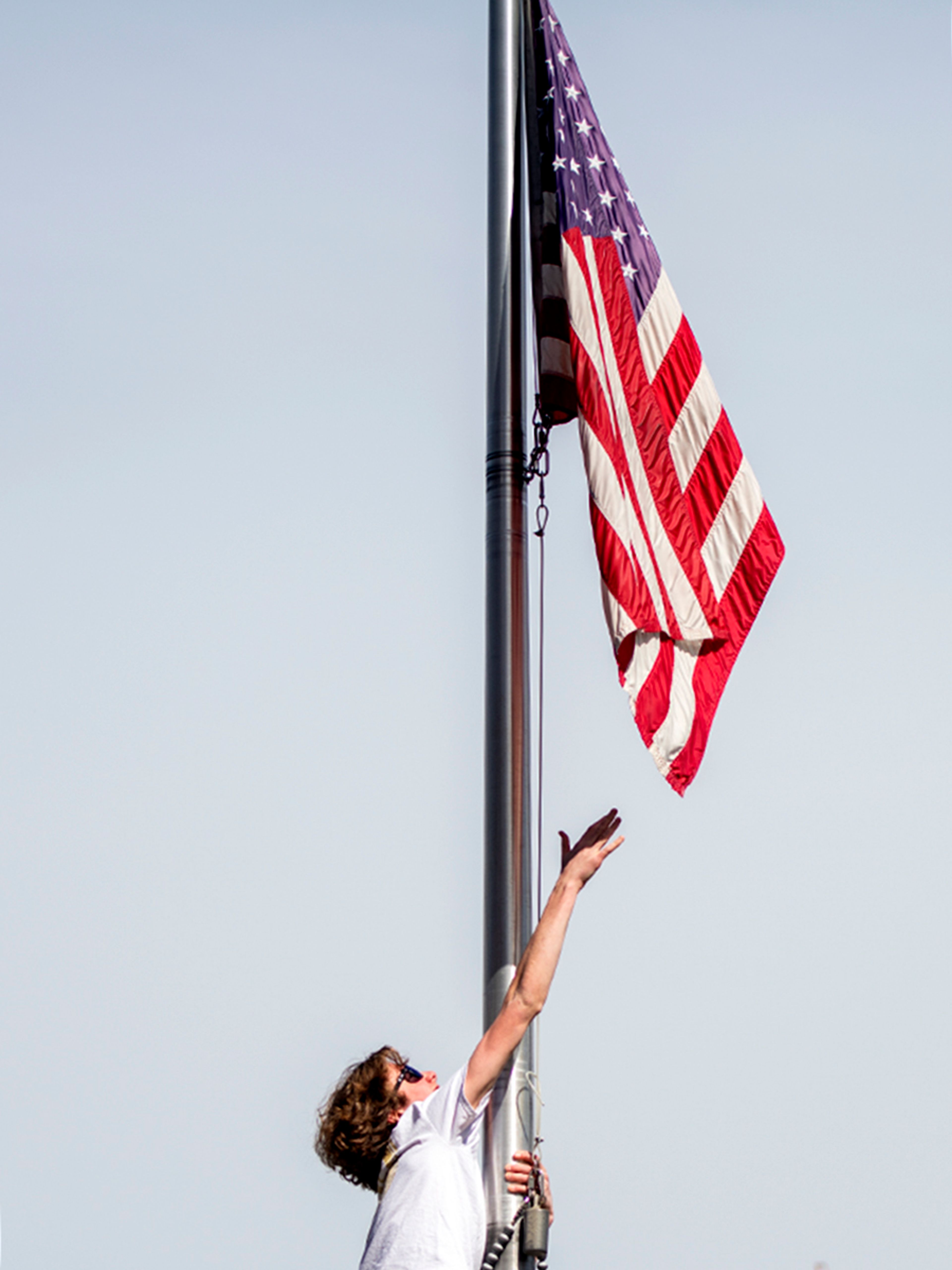 Kai Fulfer of University of Idaho’s Beta Theta Pi fraternity attempts to reach the American flag while climbing the flagpole outside of the fraternity house Thursday afternoon in Moscow.