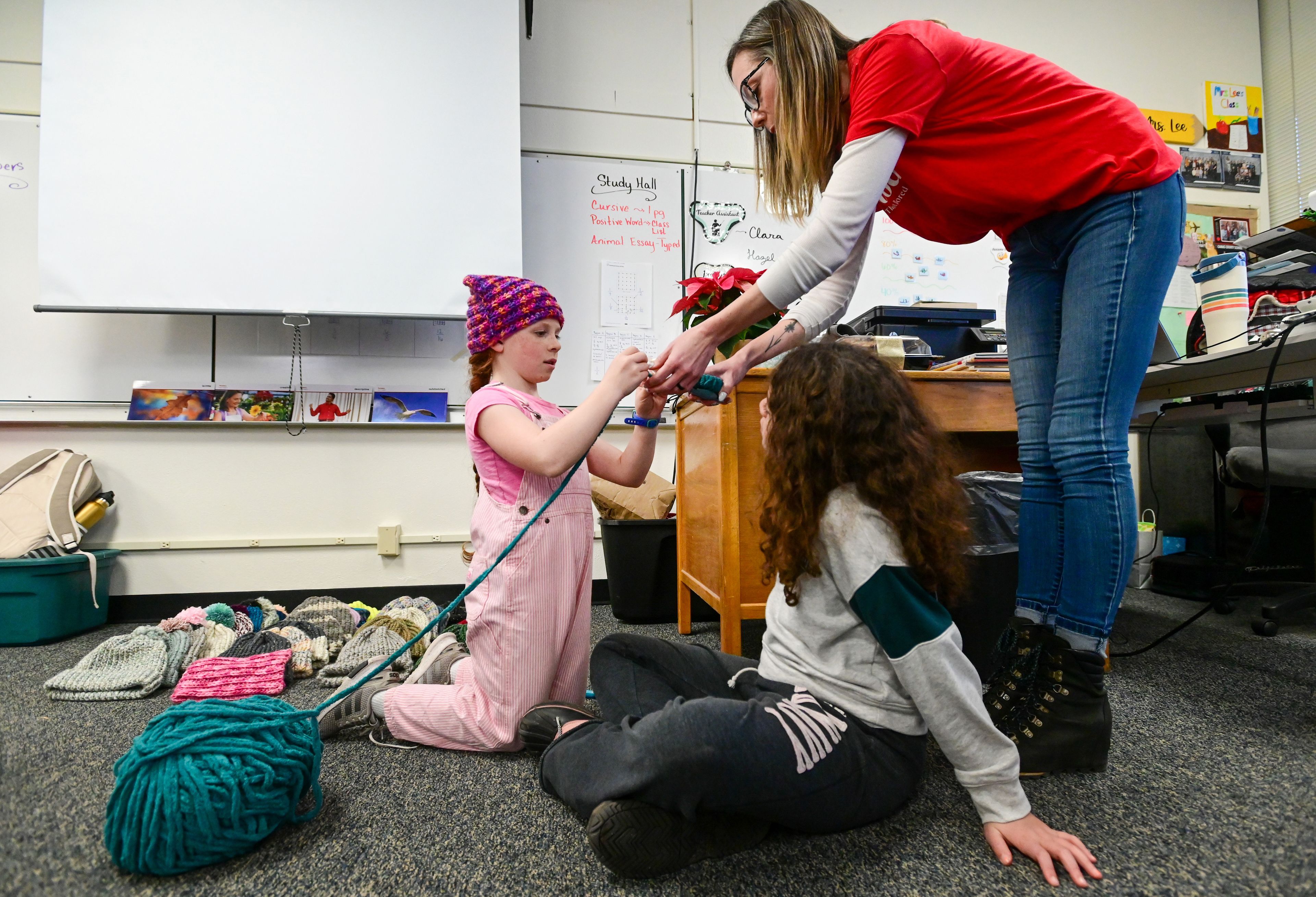 McKinley Haarr, left, a fifth-grader at Lena Whitmore Elementary School, and fourth-grader Ruth Udekwu, center, work on pom-poms for the top of their knitting club’s hats with help from fourth-grade teacher Lindsey Lee at the school in Moscow on Monday.