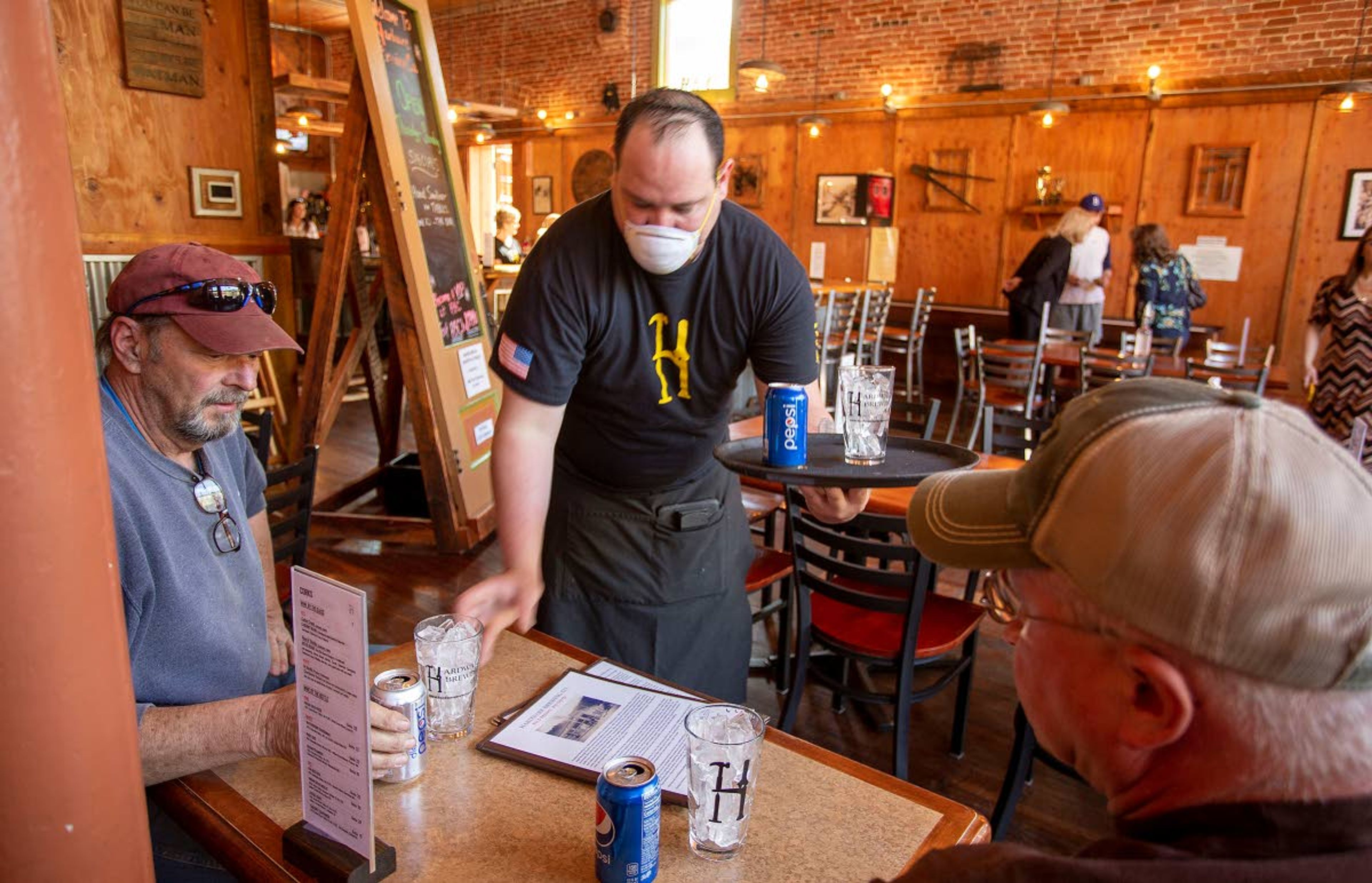 Geoff Crimmins/Daily NewsChris Mendoza (left) serves Tony Johnson (left) and Tony Johnson on May 1 at the Hardware Brewing Co. in Kendrick. Johnson and Johnson are both business owners from Moscow who came to Kendrick to support the brewery, which opened last week in violation of Gov. Brad Little’s shutdown order.