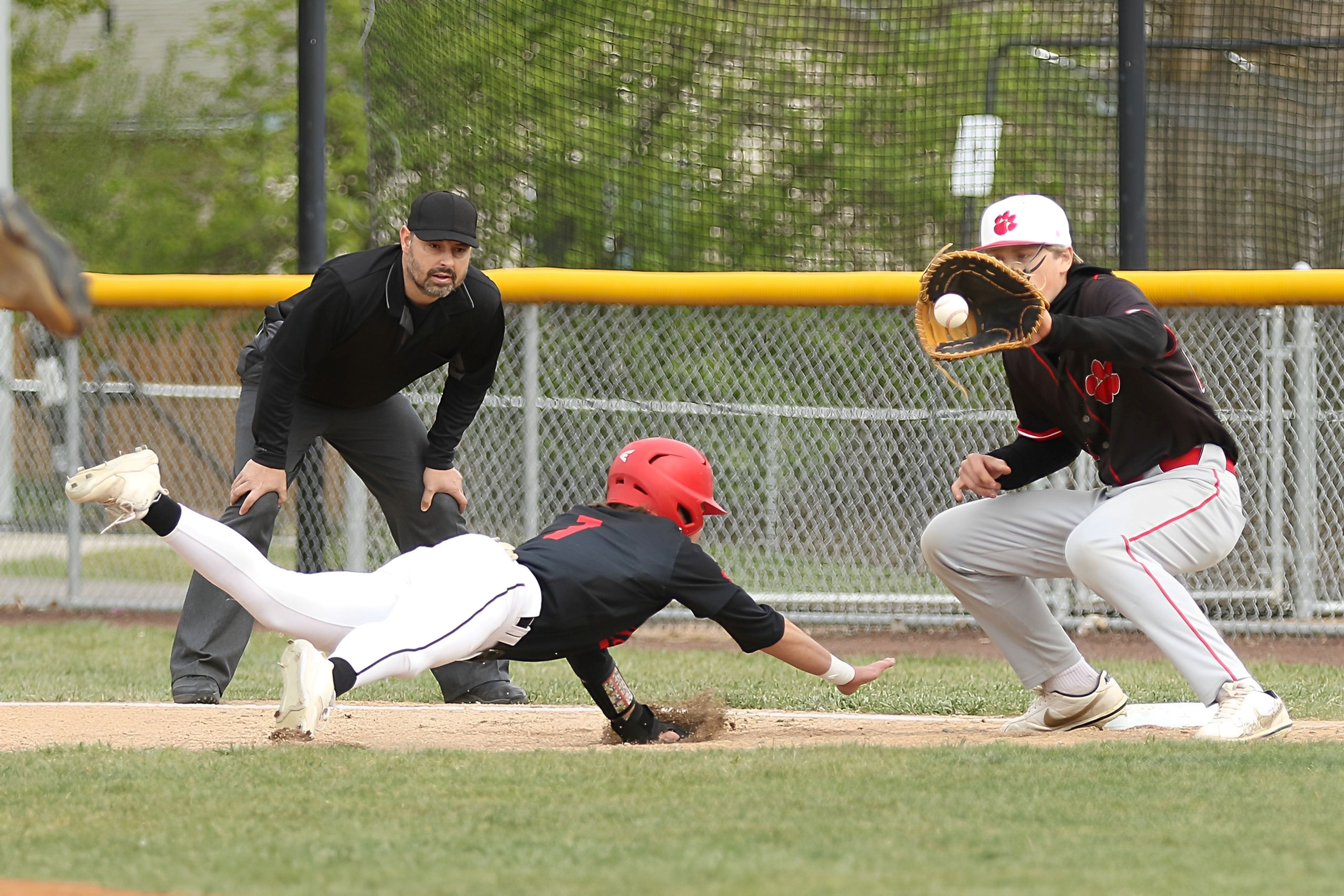 Moscow's Tyson Izzo (left) dives back to first base during an Idaho Class 4A district championship game against Sandpoint on Wednesday in Moscow.