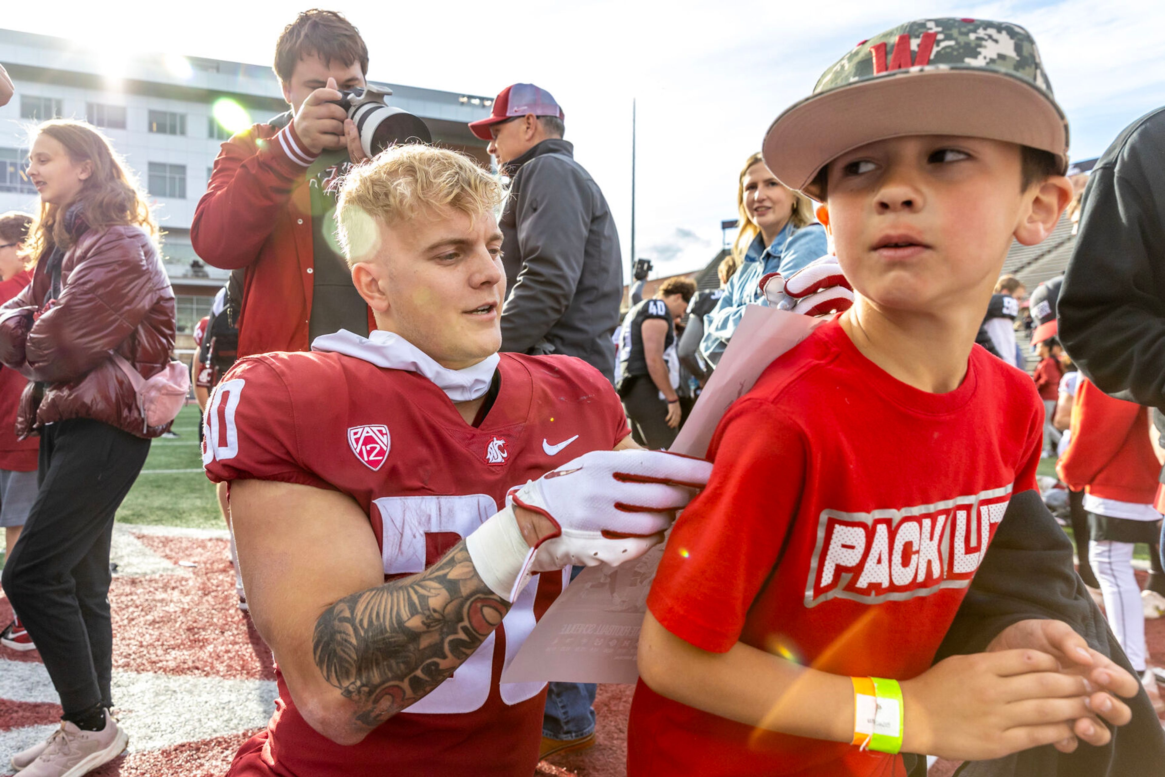 Crimson running back Dylan Paine signs a poster for a young fan after the Crimson and Gray Game at Washington State University in Pullman.