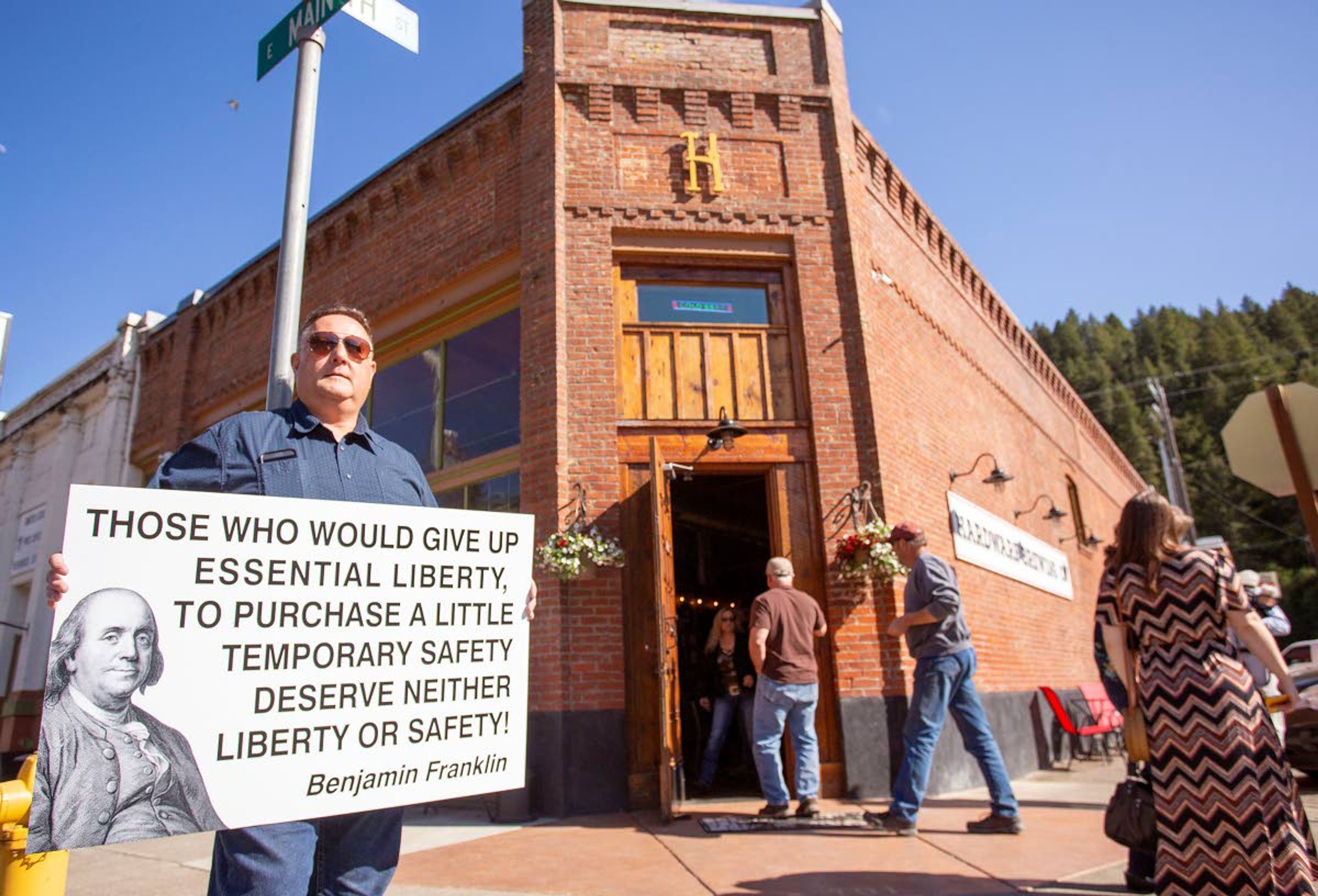 Mike Maness, of Lewiston, holds a sign at the Hardware Brewing Co. in Kendrick. The business reopened to sit-down customers recently even though Gov. Brad Little’s order still restricts restaurants to curbside and delivery sales.