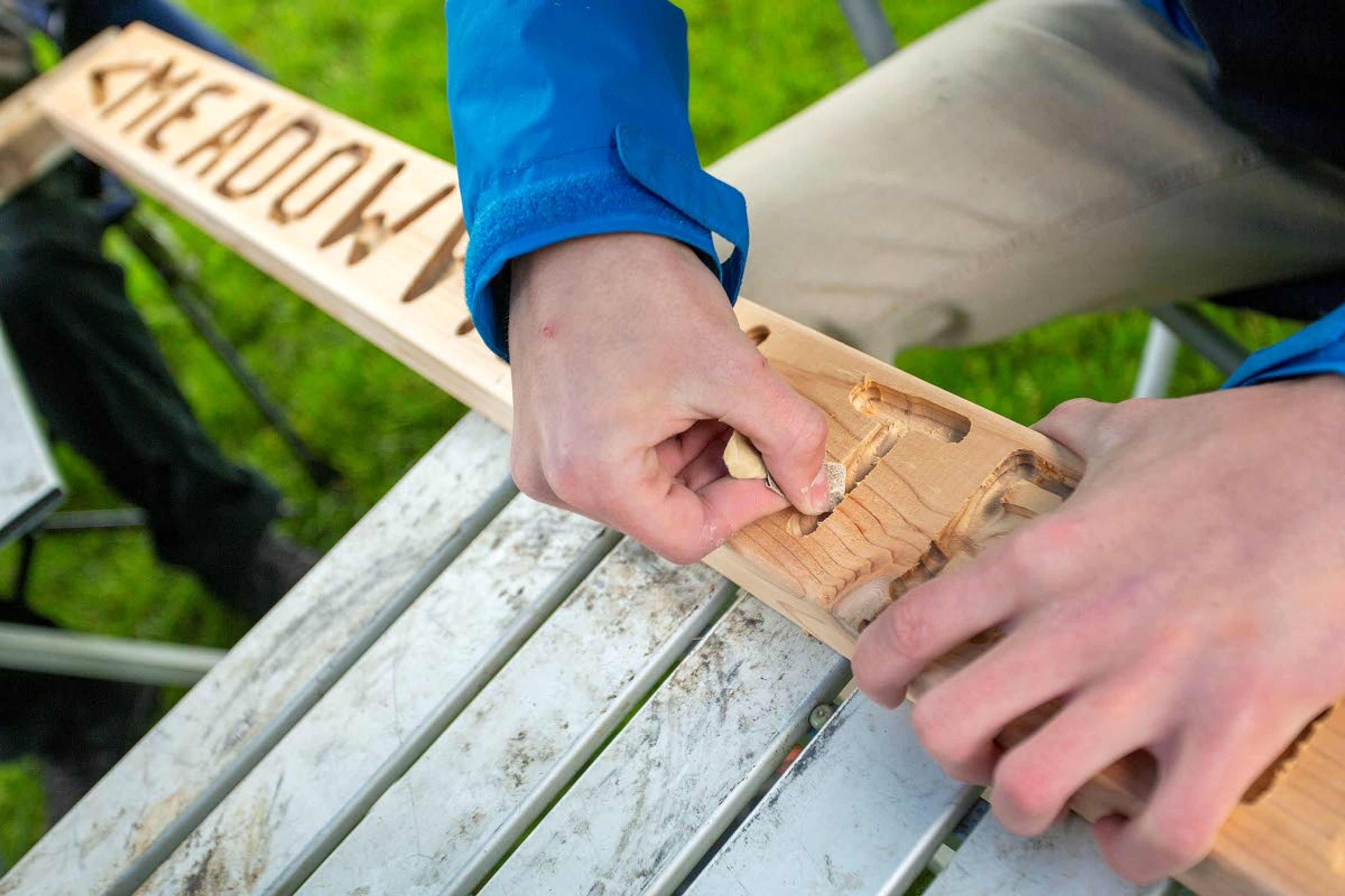 A volunteer sands a sign before staining it.