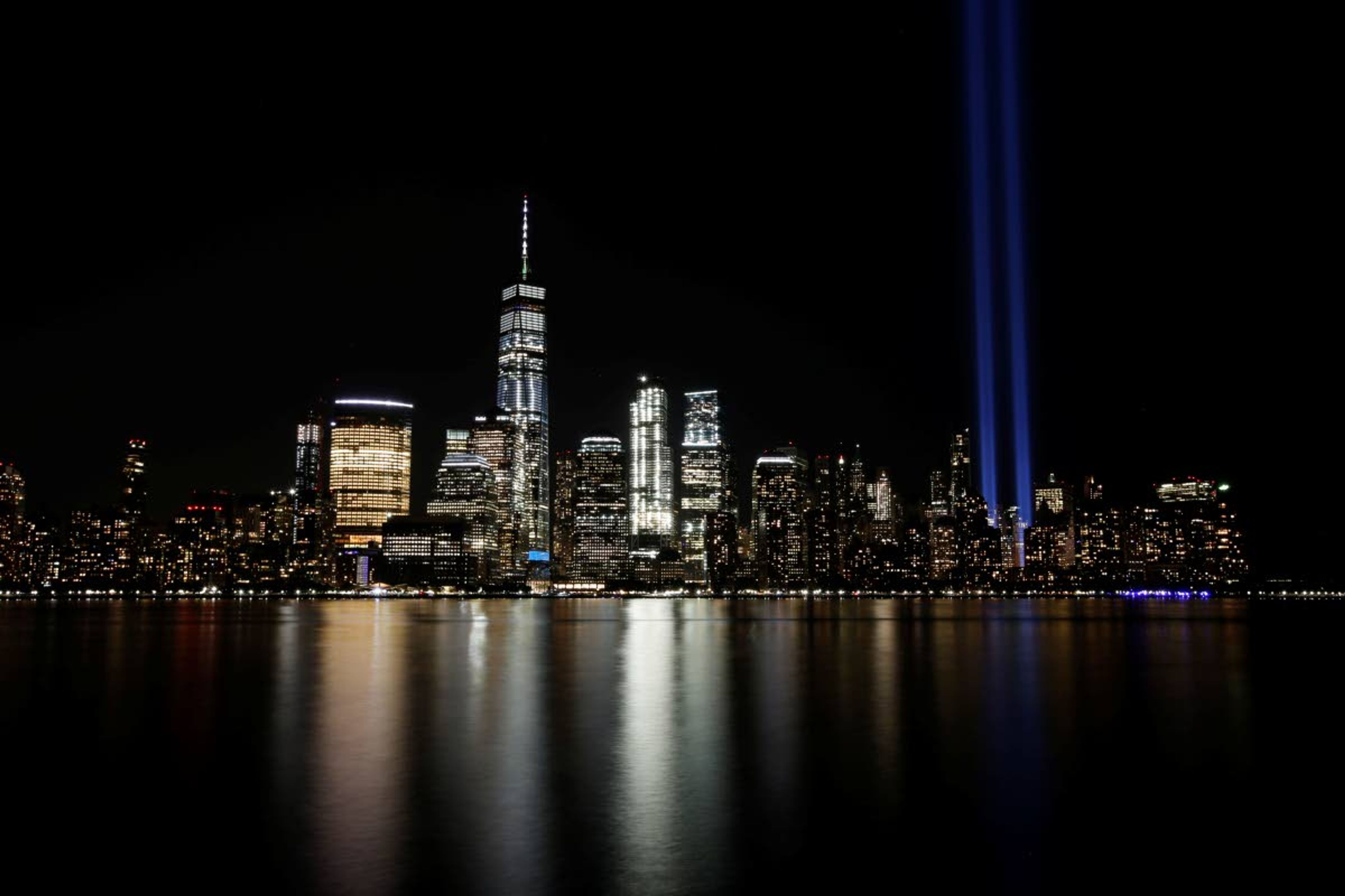 In this Sept. 11, 2017, file photo, the Tribute in Light illuminates in the sky above the Lower Manhattan area of New York, as seen from across the Hudson River in Jersey City, N.J. The coronavirus pandemic has reshaped how the U.S. is observing the anniversary of 9/11. The terror attacks’ 19th anniversary will be marked Friday, Sept. 11, 2020, by dueling ceremonies at the Sept. 11 memorial plaza and a corner nearby in New York.