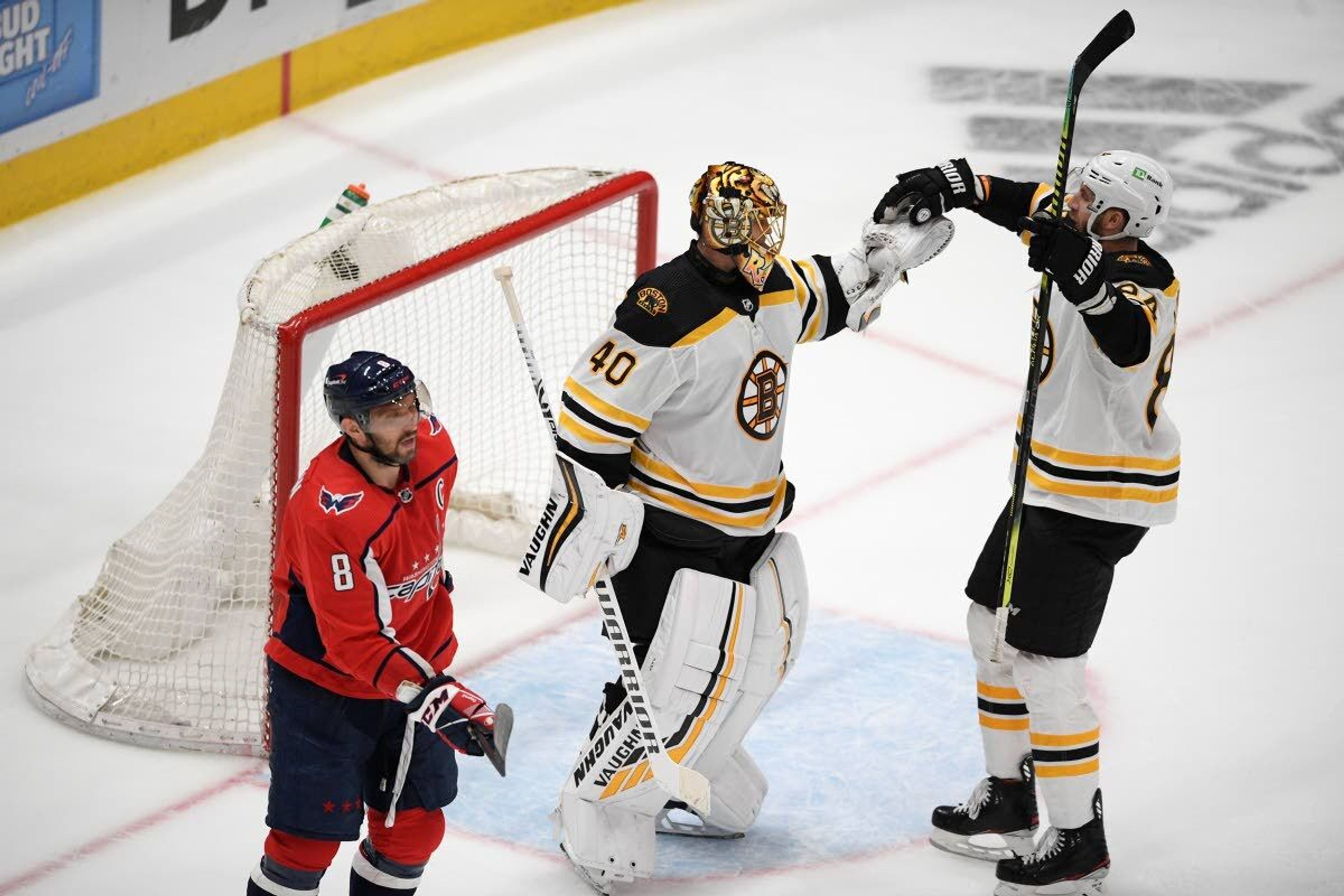 Boston Bruins goaltender Tuukka Rask (40) and defenseman Jarred Tinordi, right, celebrate after Game 5 of an NHL hockey Stanley Cup first-round playoff series as Washington Capitals left wing Alex Ovechkin (8) skates away, Sunday, May 23, 2021, in Washington. The Bruins won 3-1. (AP Photo/Nick Wass)