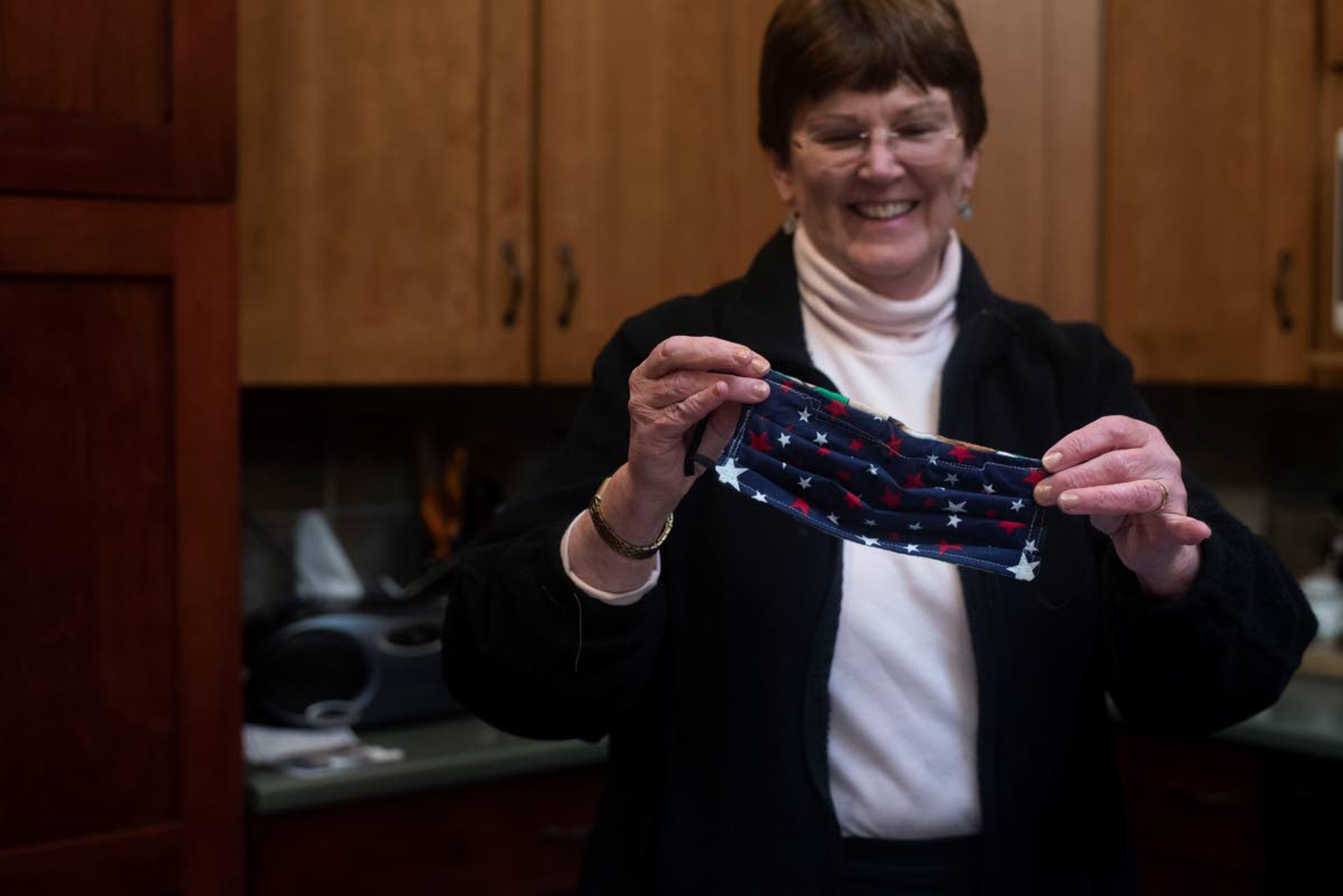 Sue Scott shows off one of the first masks she made in her apartment Wednesday. She has made newer versions of the masks to suit medical professionals’ needs.