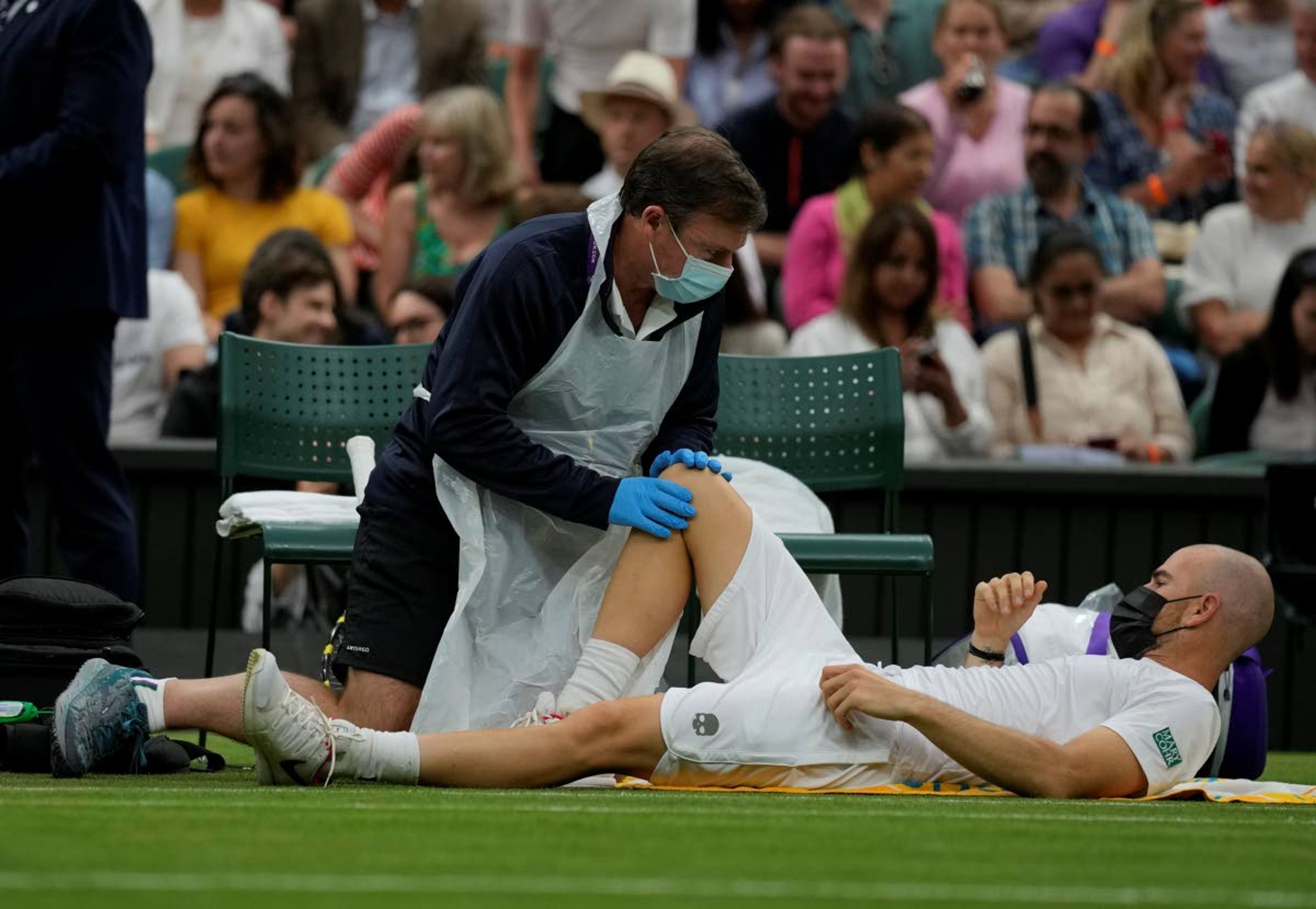 Adrian Mannarino of France receives medical care during the men's singles first round match against Switzerland's Roger Federer on day two of the Wimbledon Tennis Championships in London, Tuesday June 29, 2021. (AP Photo/Kirsty Wigglesworth)