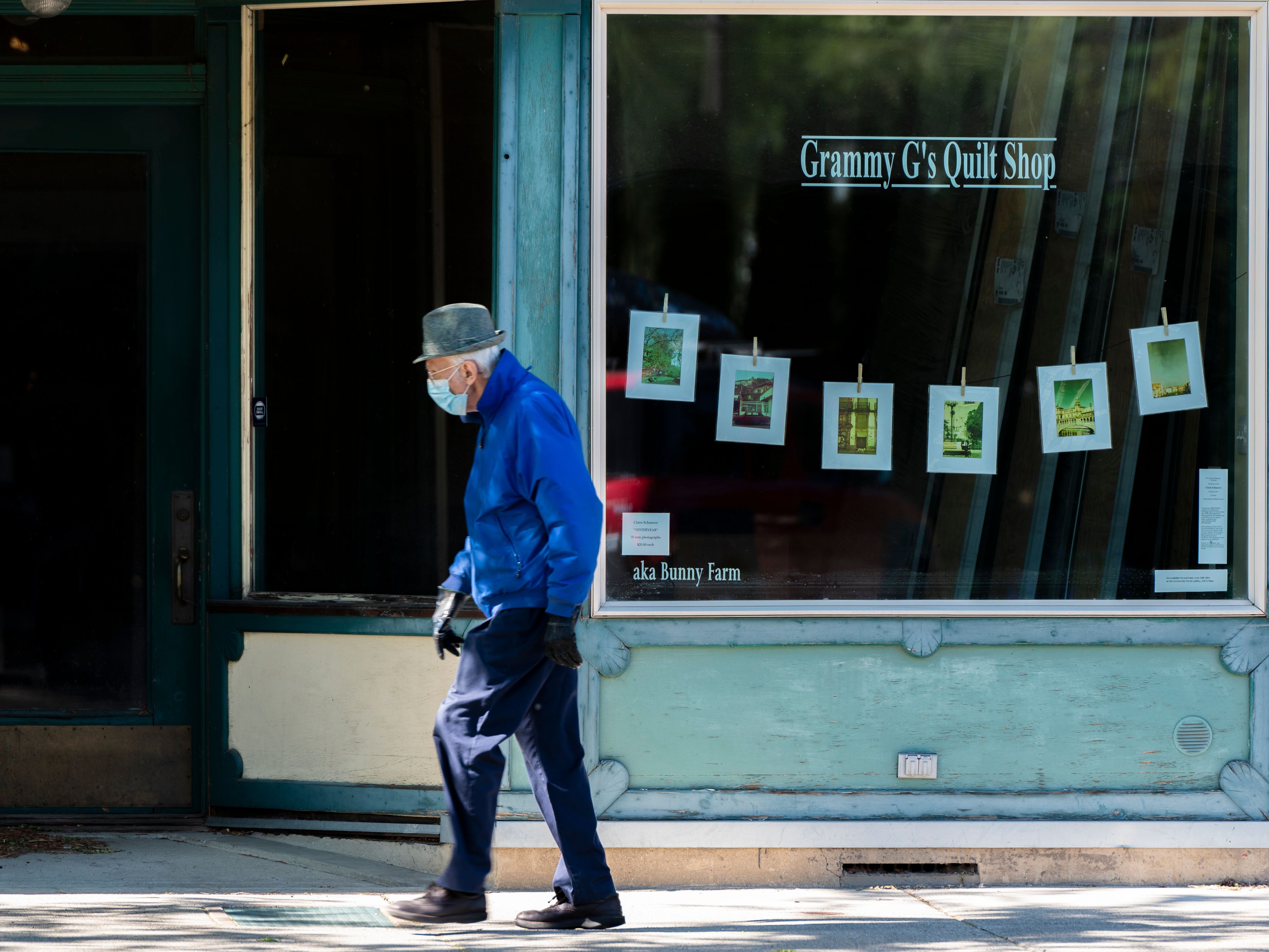 Zach Wilkinson/Daily NewsA pedestrian walks past a row of Claire Echanove’s 35mm photographs called “Yesteryears,” on the window of Grammy G’s Quilt Shop.