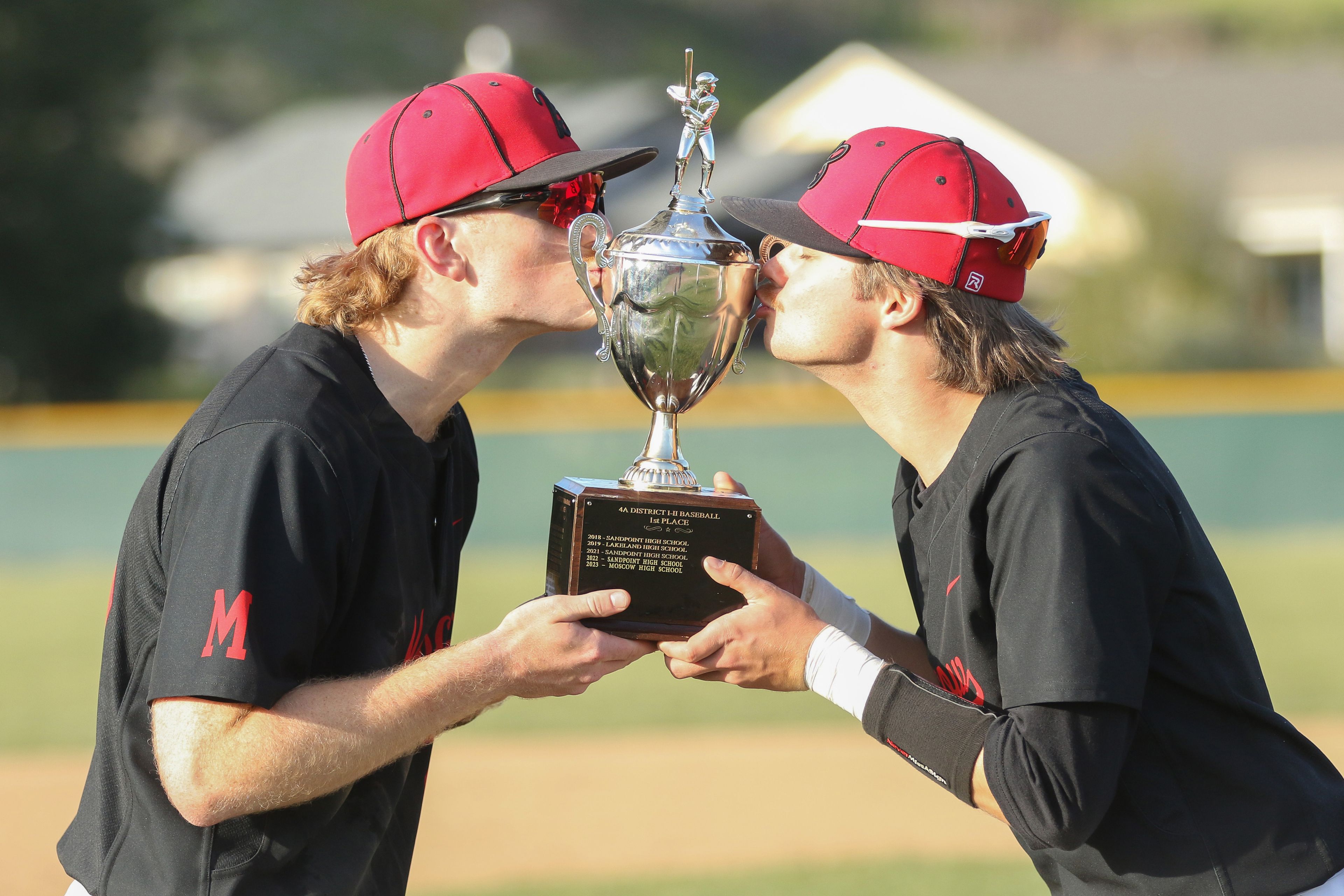 Moscow's Ethan McLaughlin, right, and Jamison Green, left, kiss the Idaho Class 4A district tournament championship trophy after a win against Sandpoint on Wednesday in Moscow.