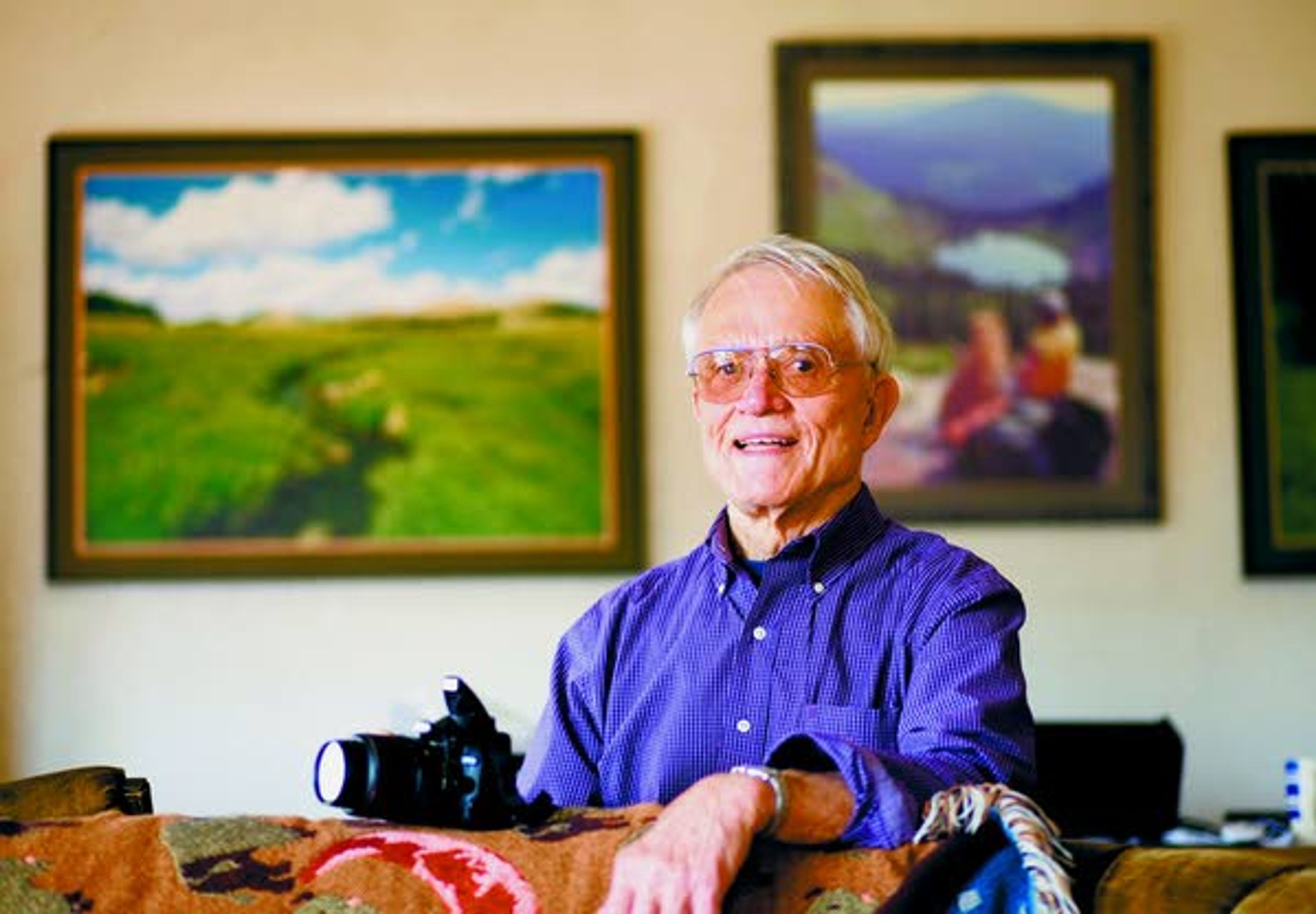 Fred Rabe is a retired biological sciences professor who enjoys photographing mountain lakes and other scenic areas. Some of his photographs hang on the wall behind him.