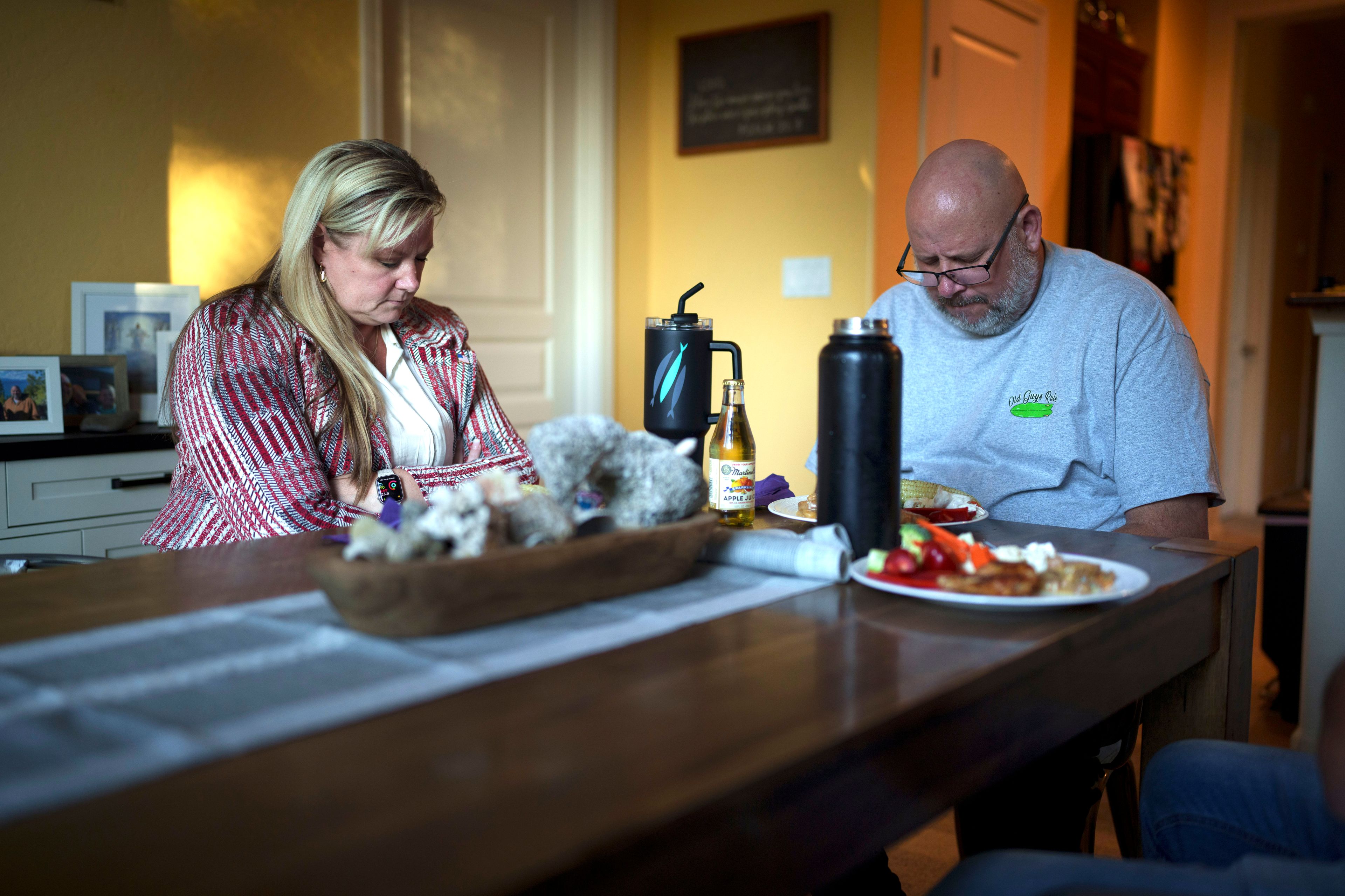 Cari-Ann Burgess, interim Registrar of Voters for Washoe County, Nev., left, prays with her husband Shane Burgess before eating dinner at their home Friday, Sept. 20, 2024, in Reno, Nev. (AP Photo/John Locher)