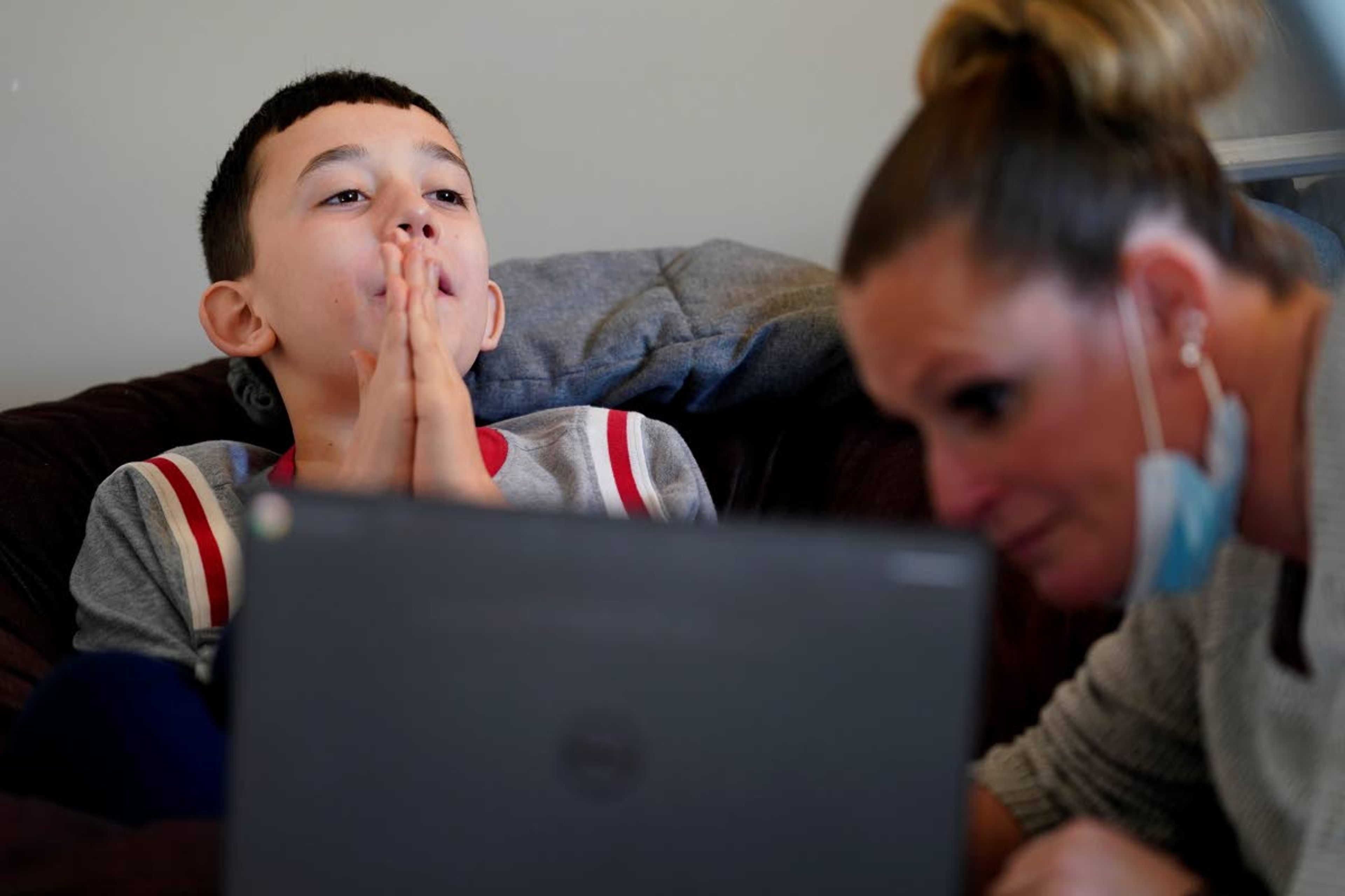 Paraprofessional Jessica Wein helps Josh Nazzaro with his school work while attending class virtually from his home in Wharton, N.J., Wednesday, Nov. 18, 2020. Without any in-school special education services for months, Nazzaro’s normally sweet demeanor has sometimes given way to aggressive meltdowns that had been under control before the pandemic. The teenager, who has autism and is nonverbal, often wanted no part of his online group speech therapy sessions, and when he did participate, he needed constant hands-on guidance from aides hired by his family. (AP Photo/Seth Wenig)