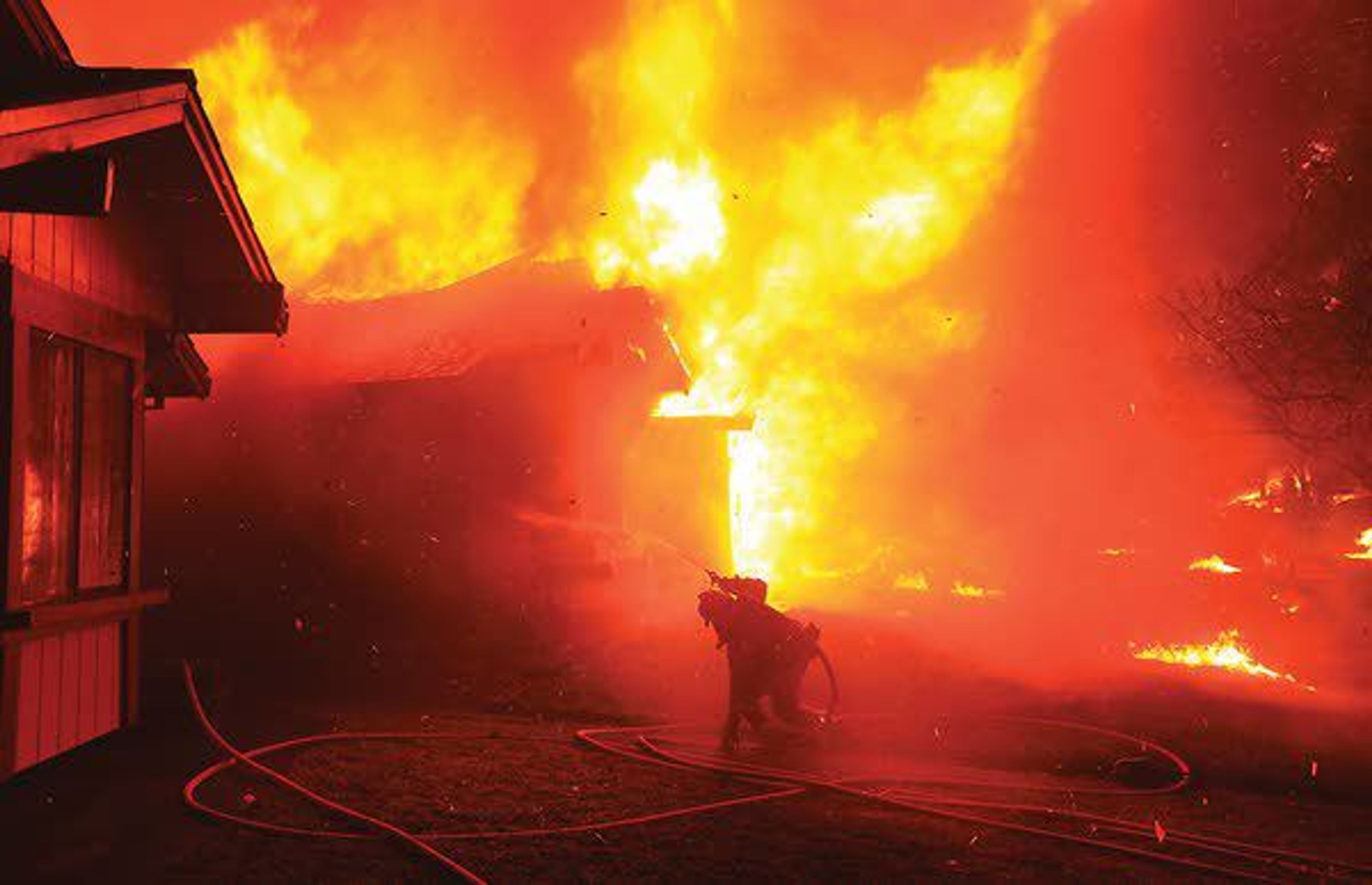 A firefighter struggles to protect a home from catching fire Oct. 9, 2017, in Coffey Park, in Santa Rosa, Calif.