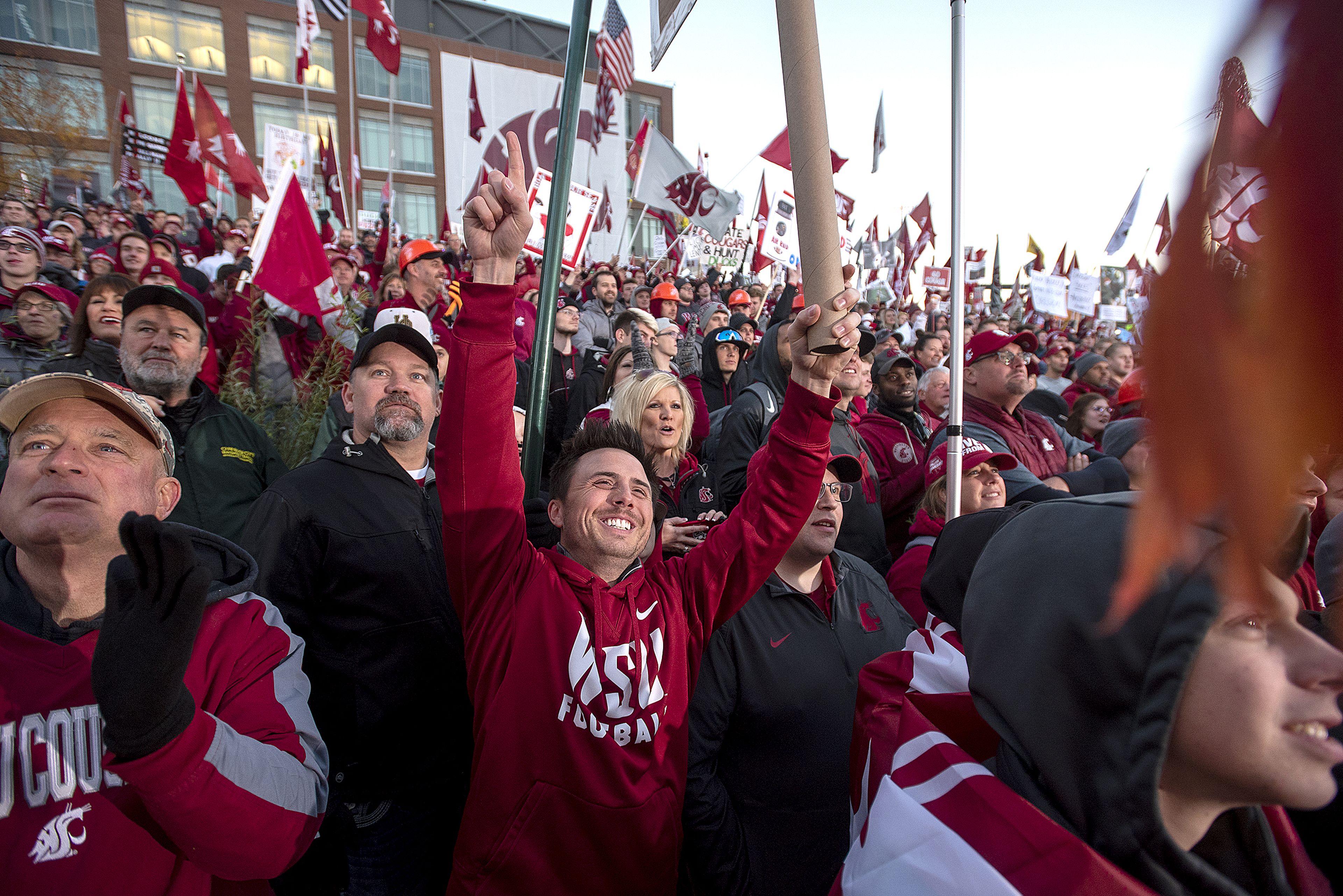 Justice Barnes of Forks, Wash., center, waves his sign while standing alongside hundreds of Cougar fans as they enjoy ESPN's live production of College GameDay on Saturday morning on the Washington State University campus in Pullman.