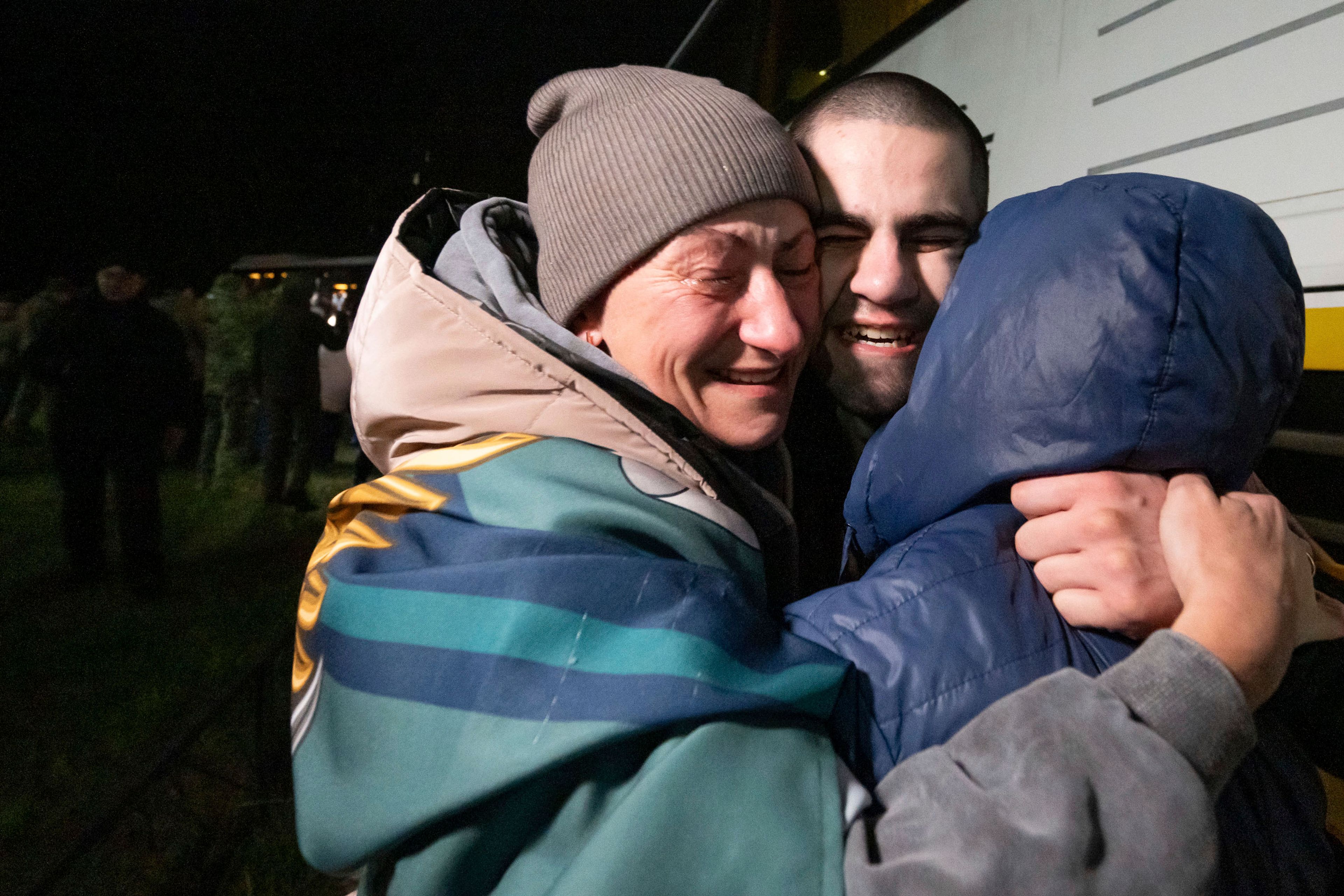 In this photo provided by the Press Service of the President of Ukraine on Oct. 19, 2024, a Ukrainian serviceman hugs his family after returning from captivity during a POWs exchange in an undisclosed location, Ukraine. (Press Service of the President of Ukraine via AP)