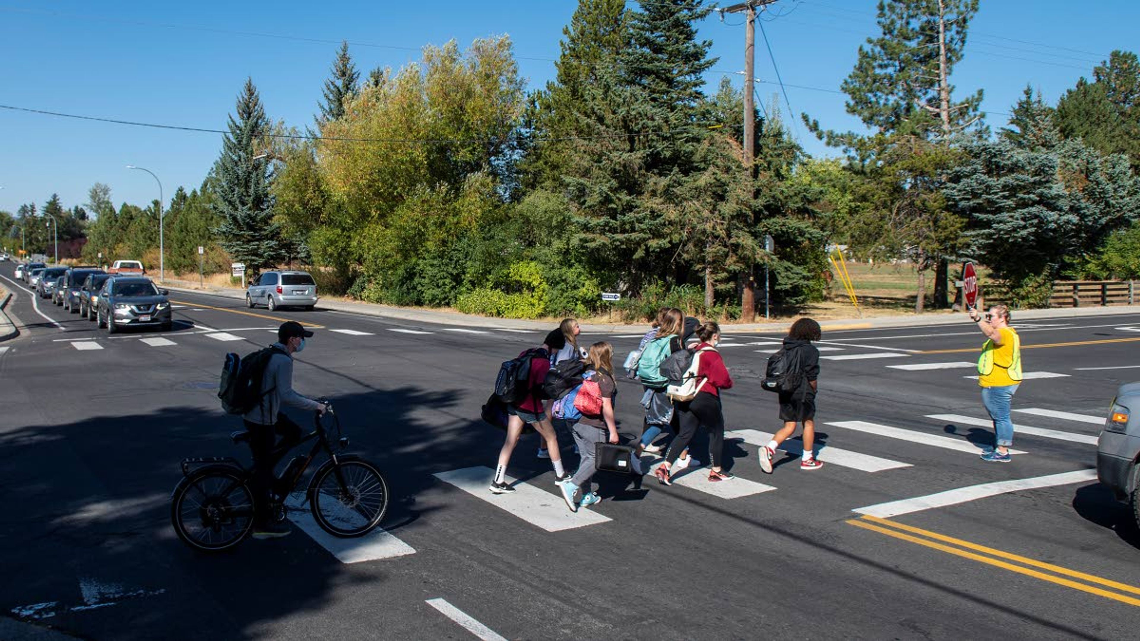 FILE — In this 2021 photo, Erin Bacon, the program coordinator for Safe Routes to School, helps young students cross the intersection of D Street and Mountain View Road as traffic begins to pile up on Tuesday afternoon in Moscow. “I want this intersection to be safe for everyone,” said Bacon.