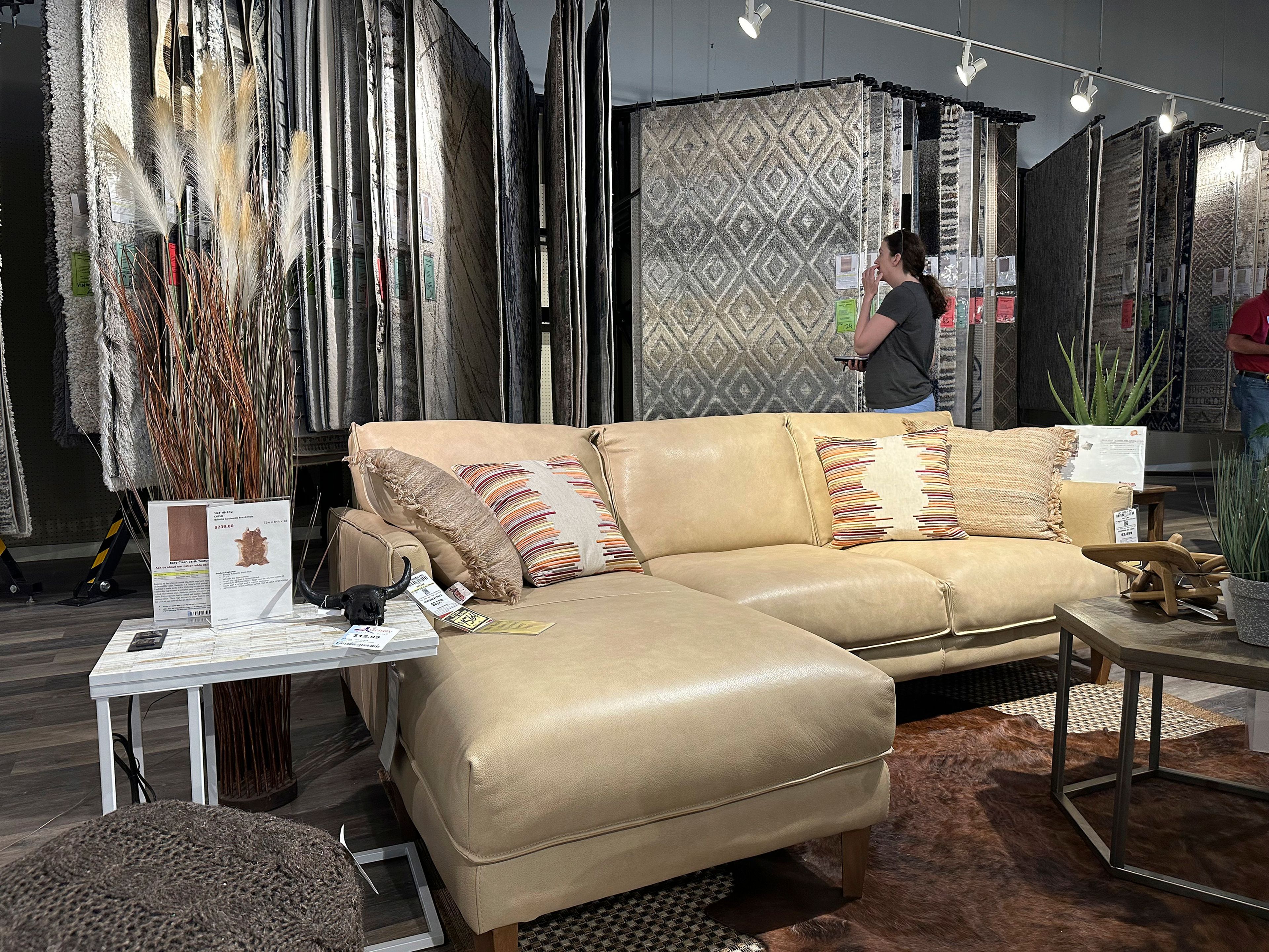 FILE - A shopper considers rug samples near a display of furniture in a store on June 2, 2024, in Lone Tree, Colo. (AP Photo/David Zalubowski, File)