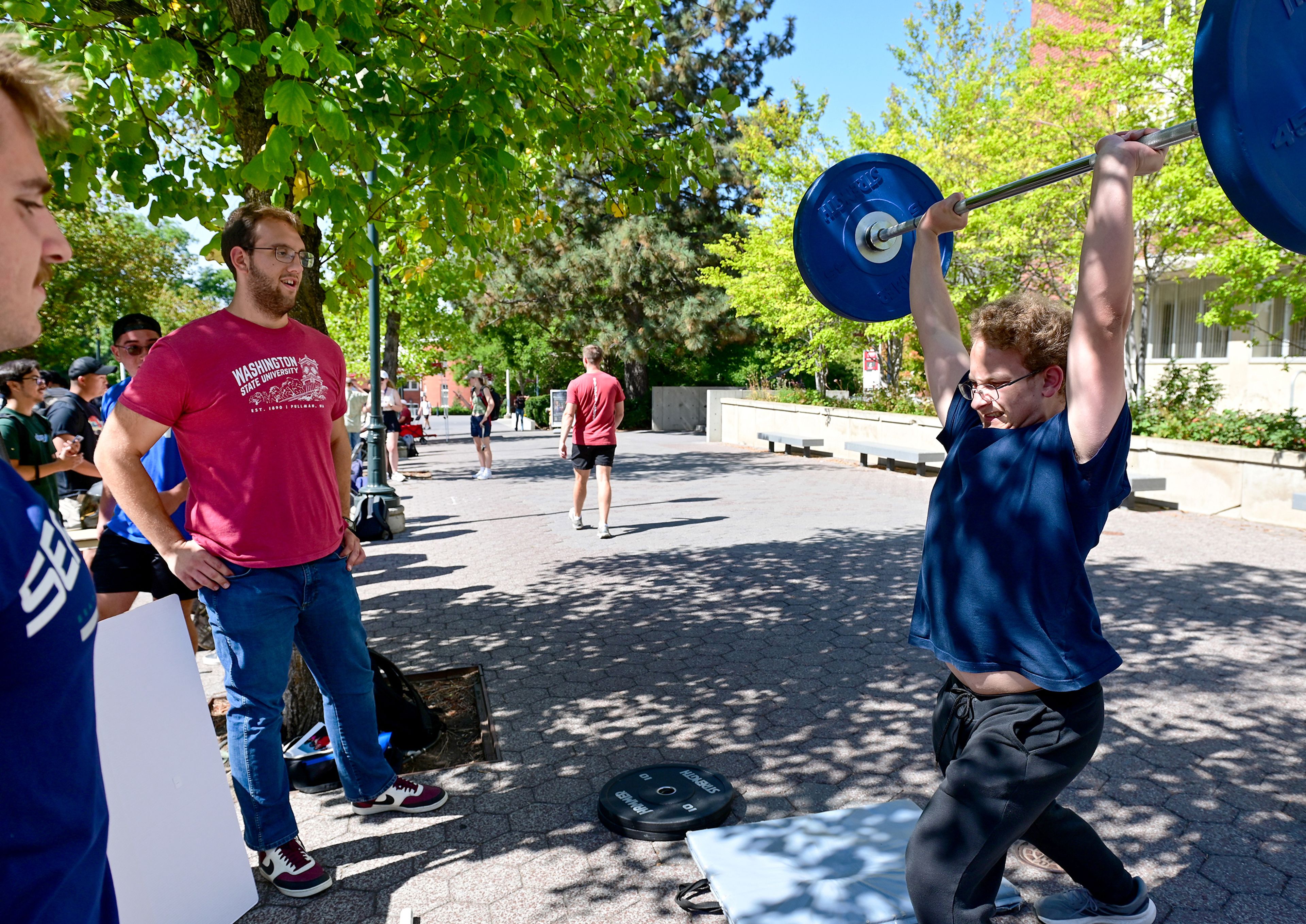 Aron Seigal, right, a member of the WSU Olympic Weightlifting club, demonstrates a lift at the Get Involved Fair Wednesday along Glenn Terrell Mall on campus in Pullman.