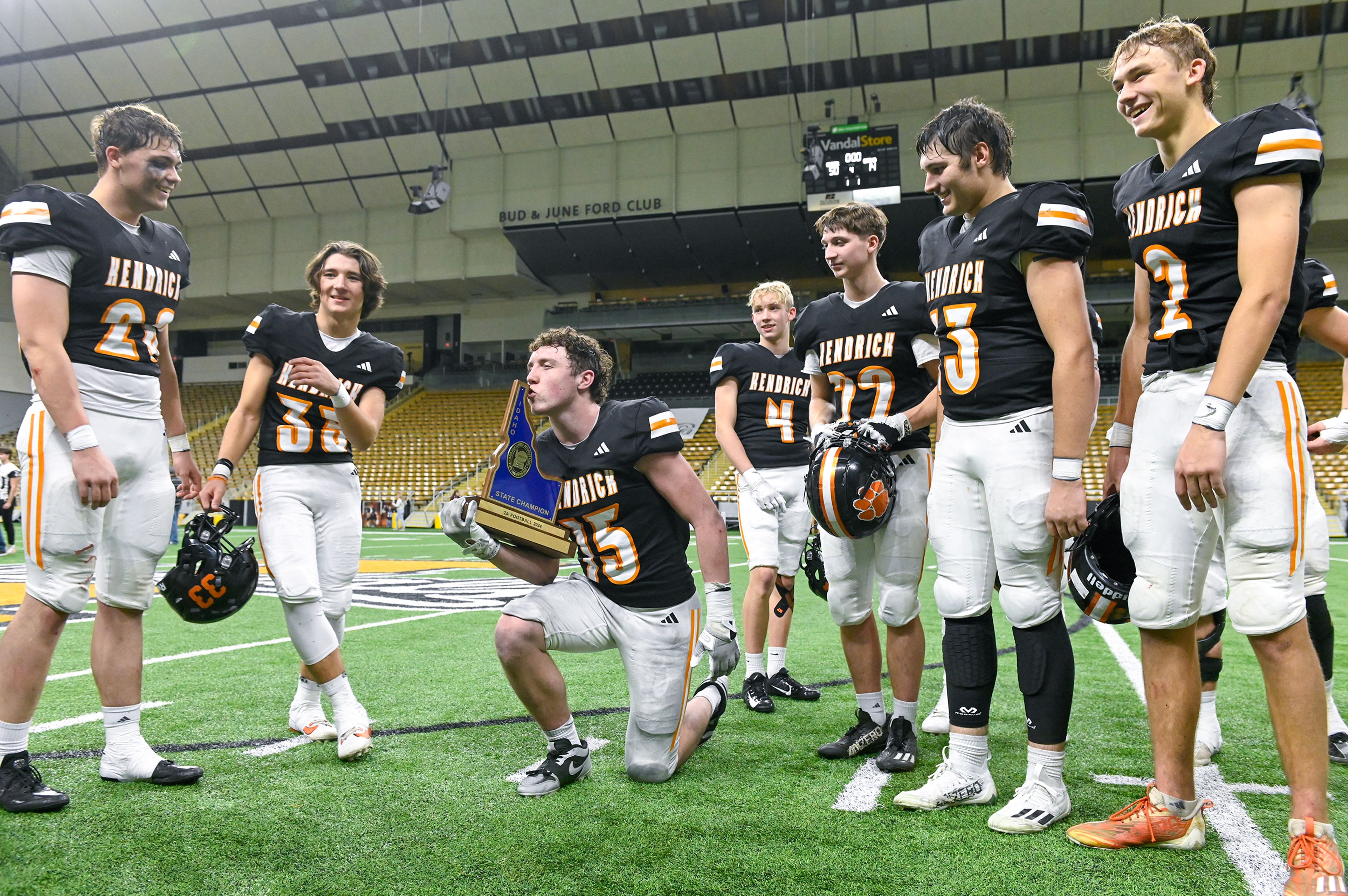 Kendrick’s Xavier Carpenter pauses walking off the field to pose with the trophy for the Idaho Class 2A state championship win over Butte County Friday at the P1FCU Kibbie Dome in Moscow.