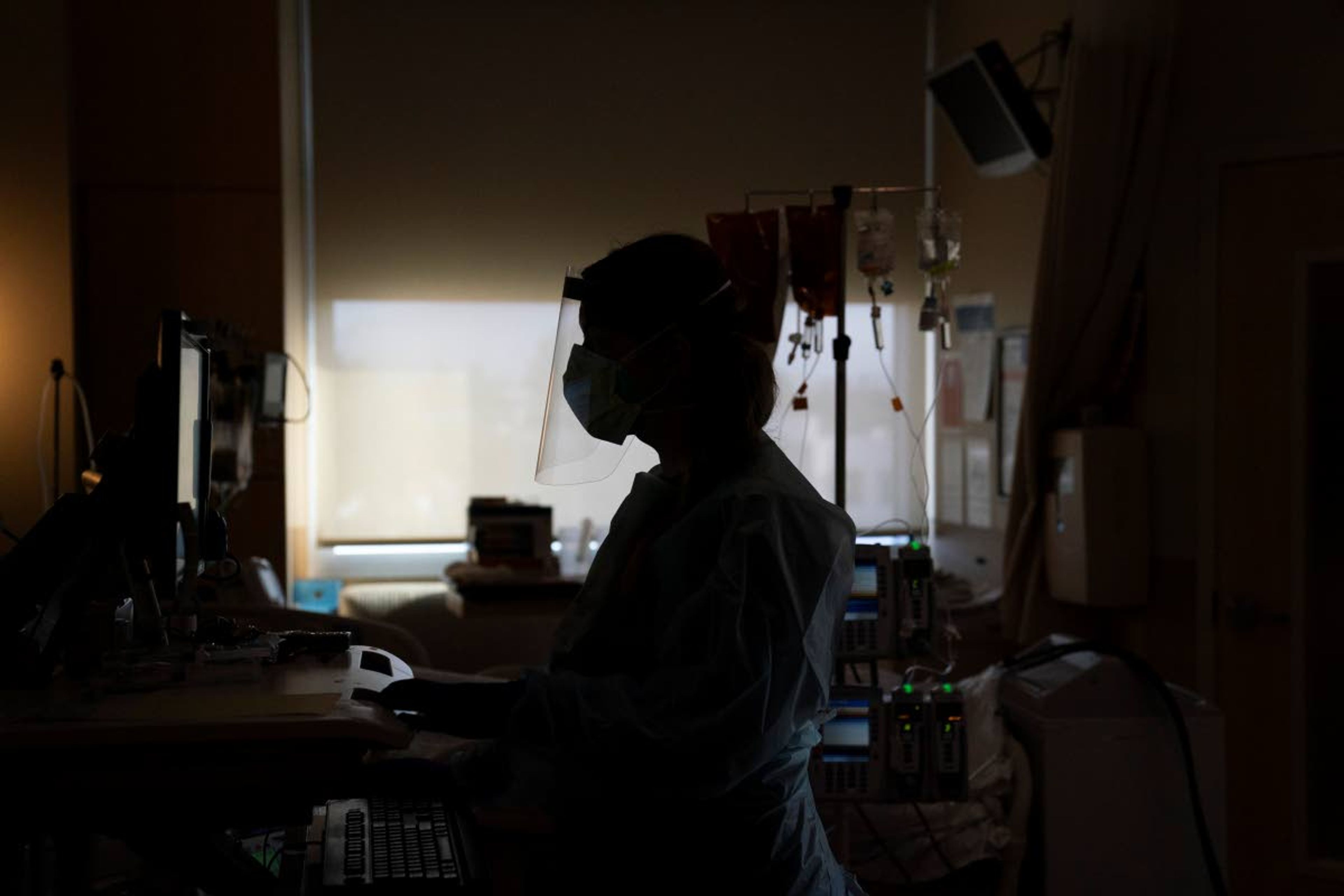 FILE - In this Nov. 19, 2020, file photo, a nurse works on a computer while assisting a COVID-19 patient at a hospital in Los Angeles. Across the country, doctors and nurses on the front lines of the coronavirus pandemic are dealing with hostility, threats and violence from patients angry over safety rules designed to keep the virus from spreading. (AP Photo/Jae C. Hong, File)