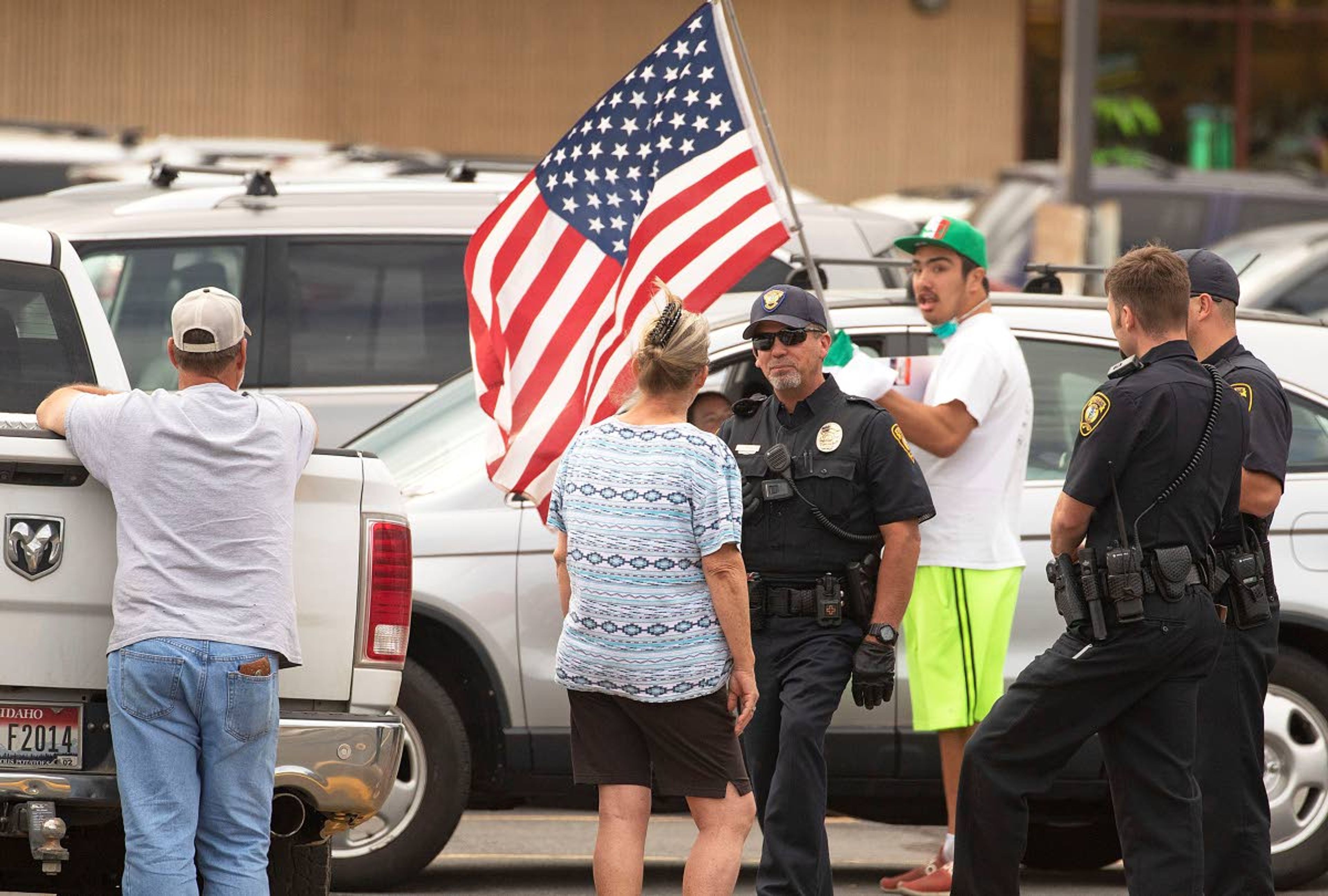 Photos by Geoff Crimmins/Daily NewsMoscow Police officers talk to a woman after she reportedly yelled at David Tolman, center, and tried to grab his flag while he was flying it upside down as a sign of distress while protesting in response to the death of George Floyd on Friday on North Main Street in Moscow. “I’m here to show some love and respect,” Tolman said. Police Chief James Fry said officers separated the two people, and that no one was cited or arrested. Tolman later turned his flag right side up.