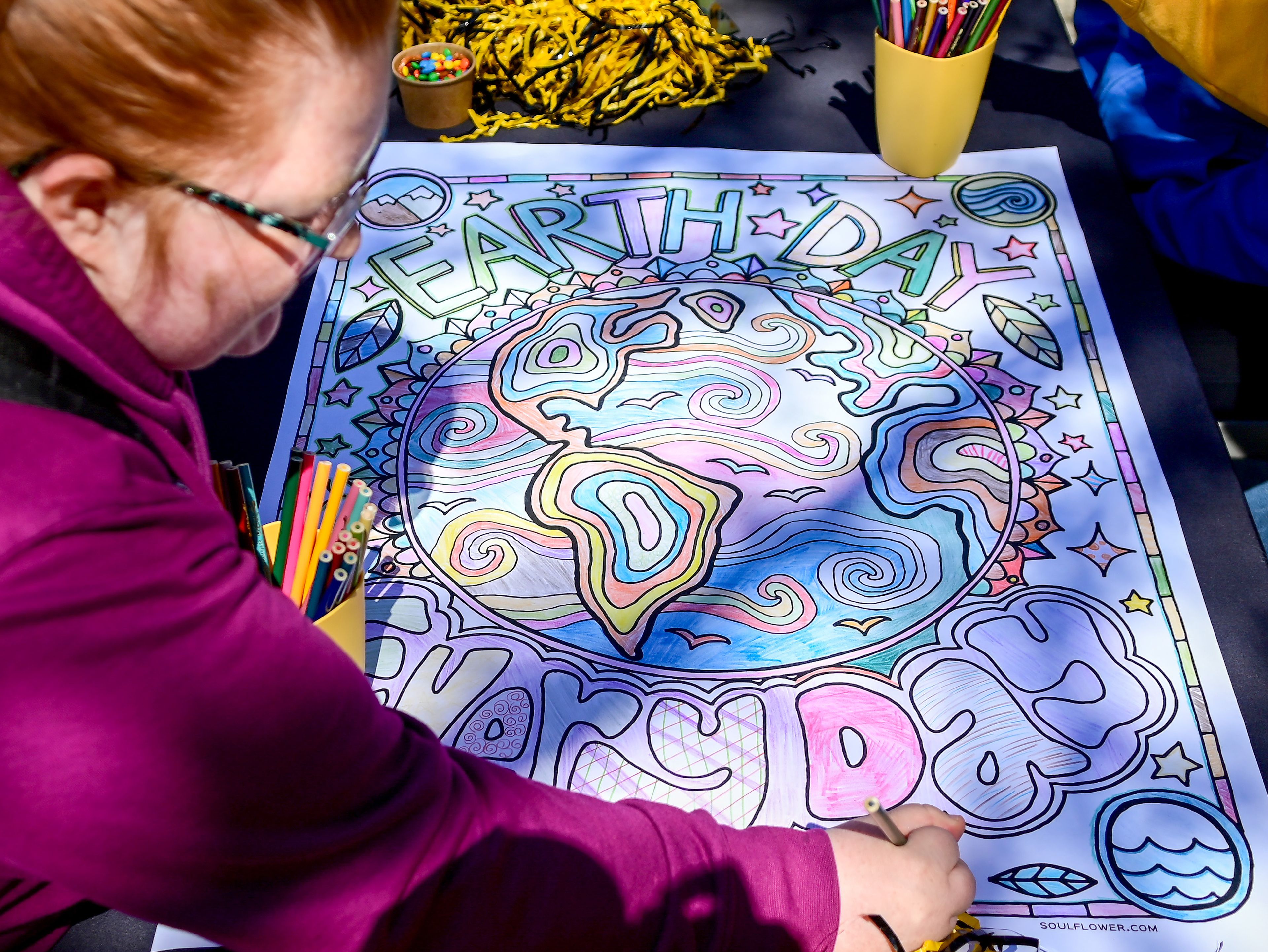 Alisa Hopf, a University Idaho student staff member with Housing and Residence Life, colors in a portion of an Earth Day poster at the group’s booth during the Earth Jam celebration on campus in Moscow on Monday.