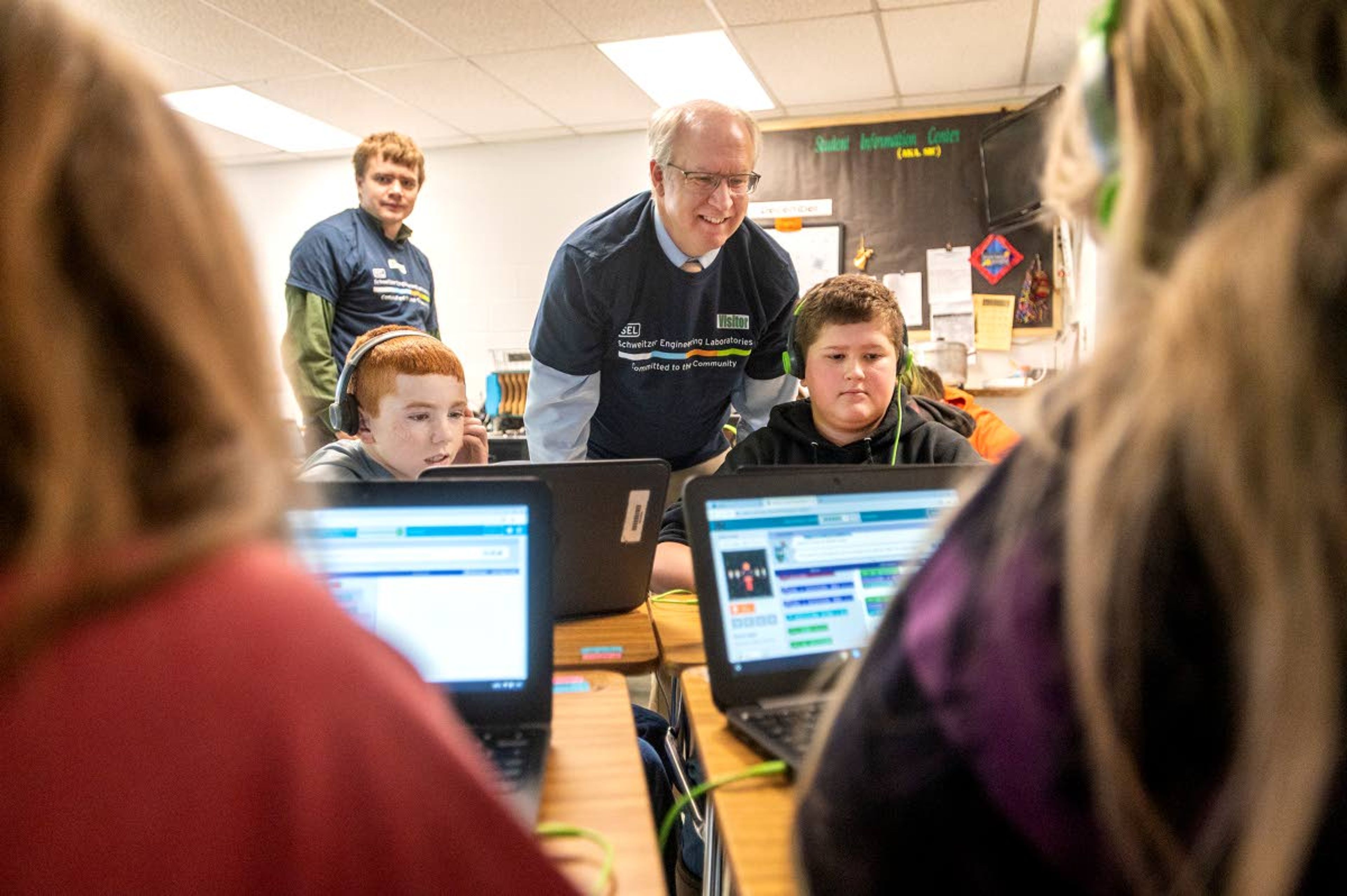 Paul Stoaks, an engineering manager at Schweitzer Engineering Laboratories, assists Kason Heitstuman, 12, left, and Hunter Ely, 11, as they practice coding Friday afternoon at Potlatch Elementary.