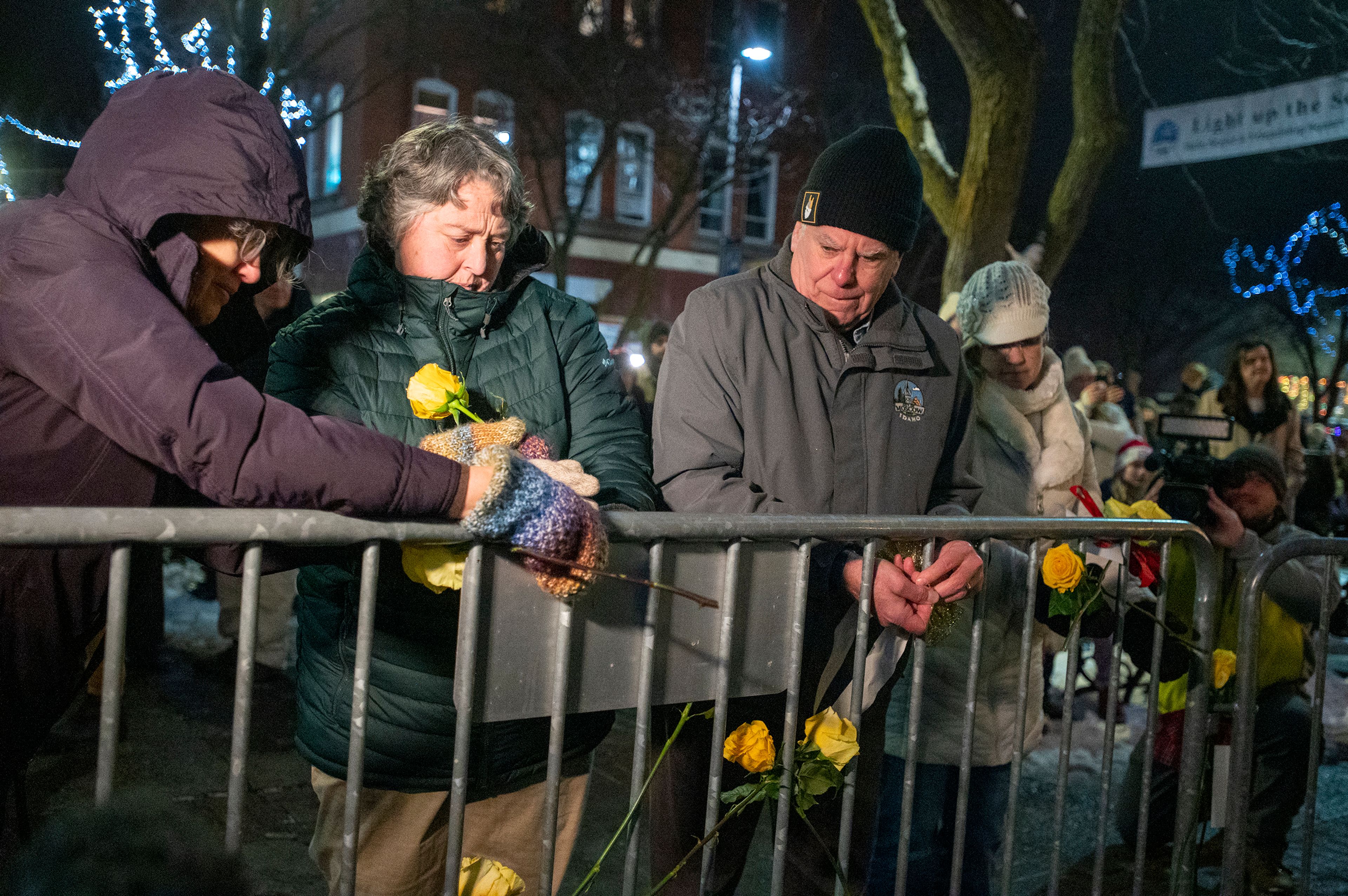 Sandra Kelly, second from left, and Mayor Art Bettge wrap yellow roses around the fence of the Winter Wonderland Tree in Friendship Square in honor of Kaylee Goncalves, Madison Mogen, Xana Kernodle and Ethan Chapin during the Light up the Season Parade in Moscow on Thursday.