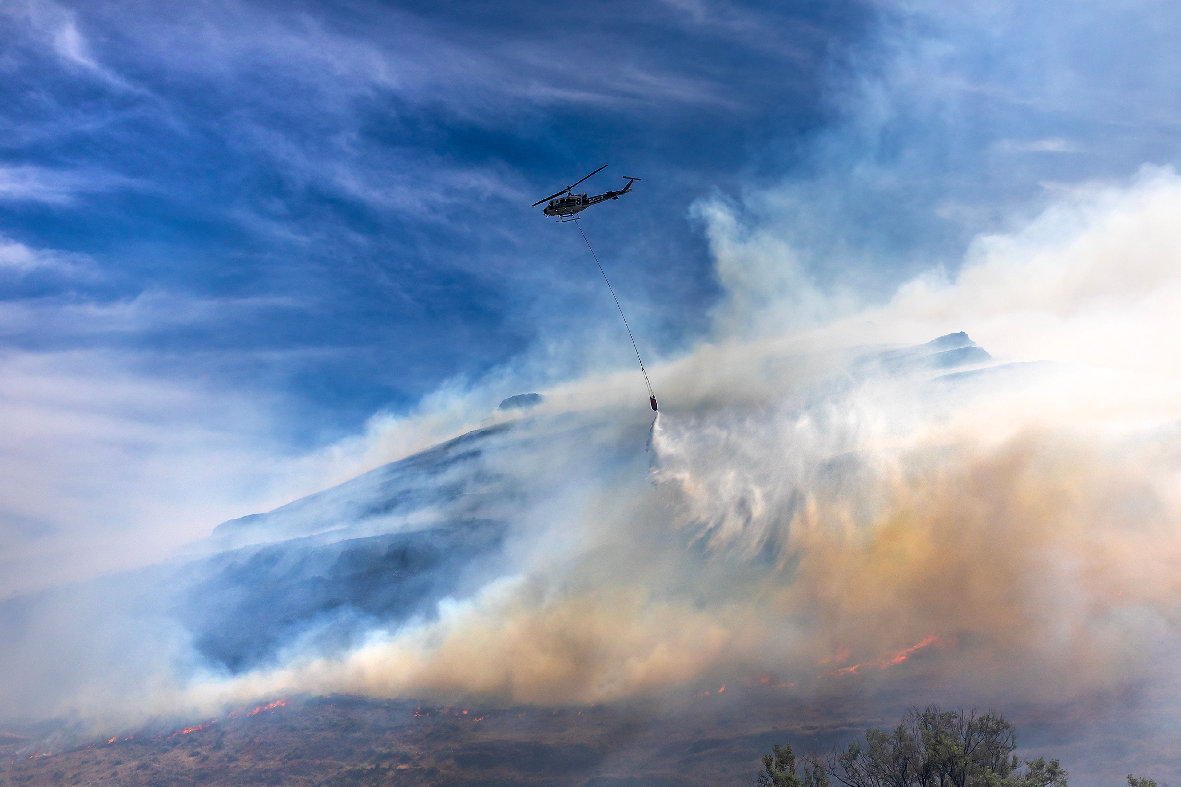 A helicopter makes a drop on a fire moving along the hillside by Nisqually John Landing off of Wawawai Road on Friday.