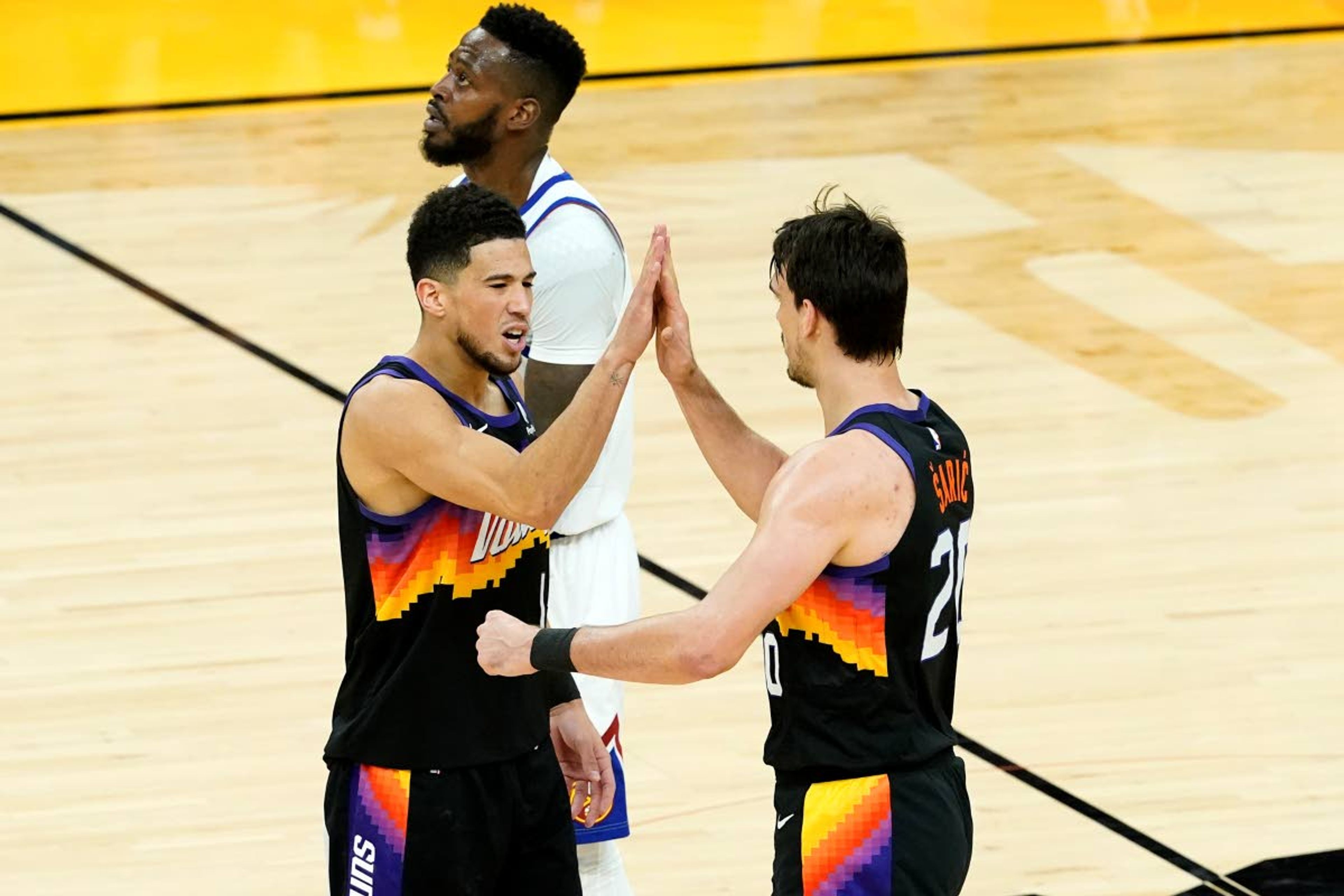 Phoenix Suns guard Devin Booker, left, high fives forward Dario Saric after a three pointer against the Denver Nuggets during the first half of Game 2 of an NBA basketball second-round playoff series, Wednesday, June 9, 2021, in Phoenix. (AP Photo/Matt York)