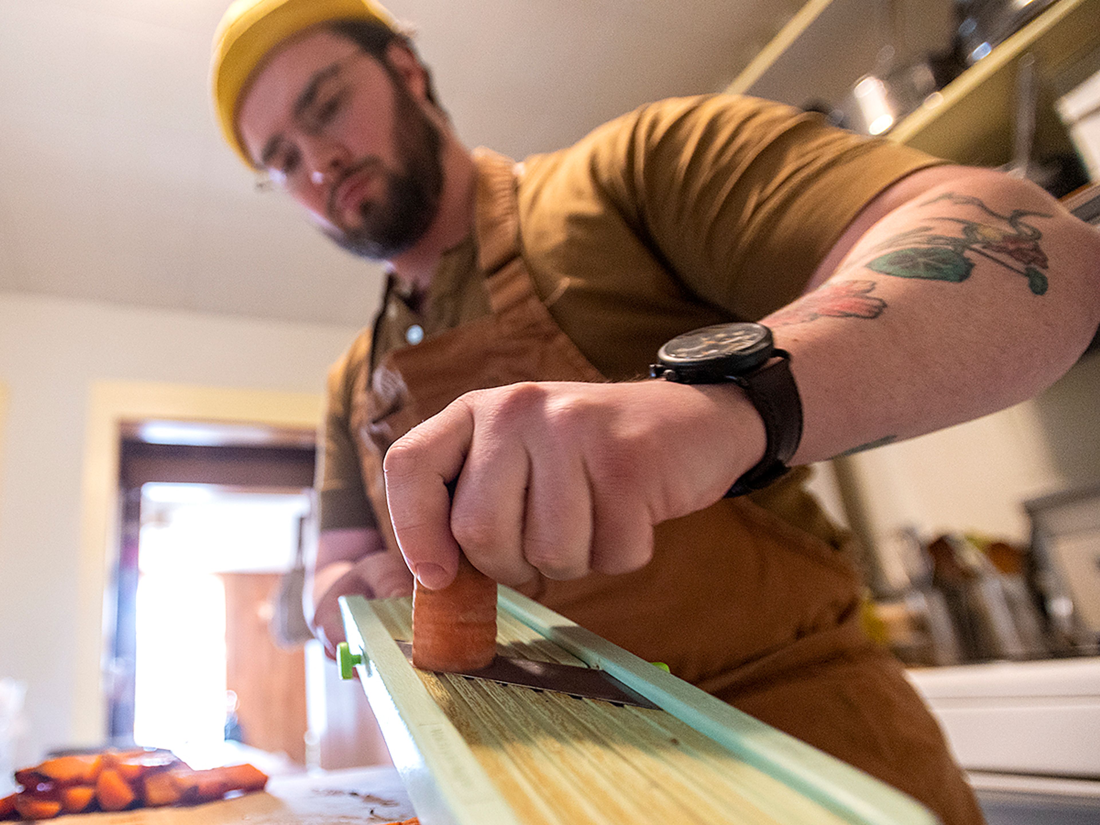 Ian Pecoraro shaves beef fat-roasted Ronnigers farms carrots, while preparing a typical Cellar Door Cooking dish.